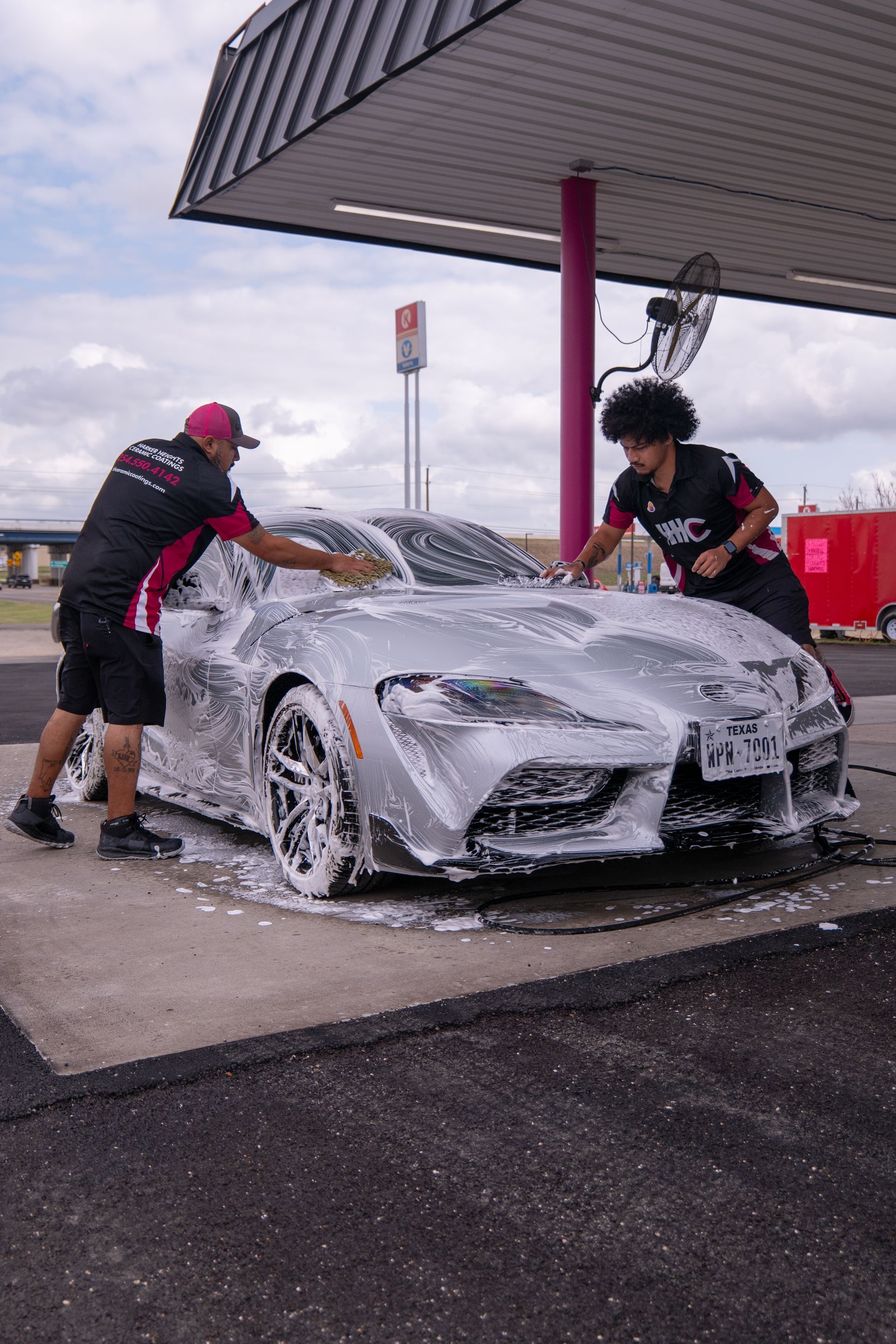 A white sports car is covered in foam in a garage.