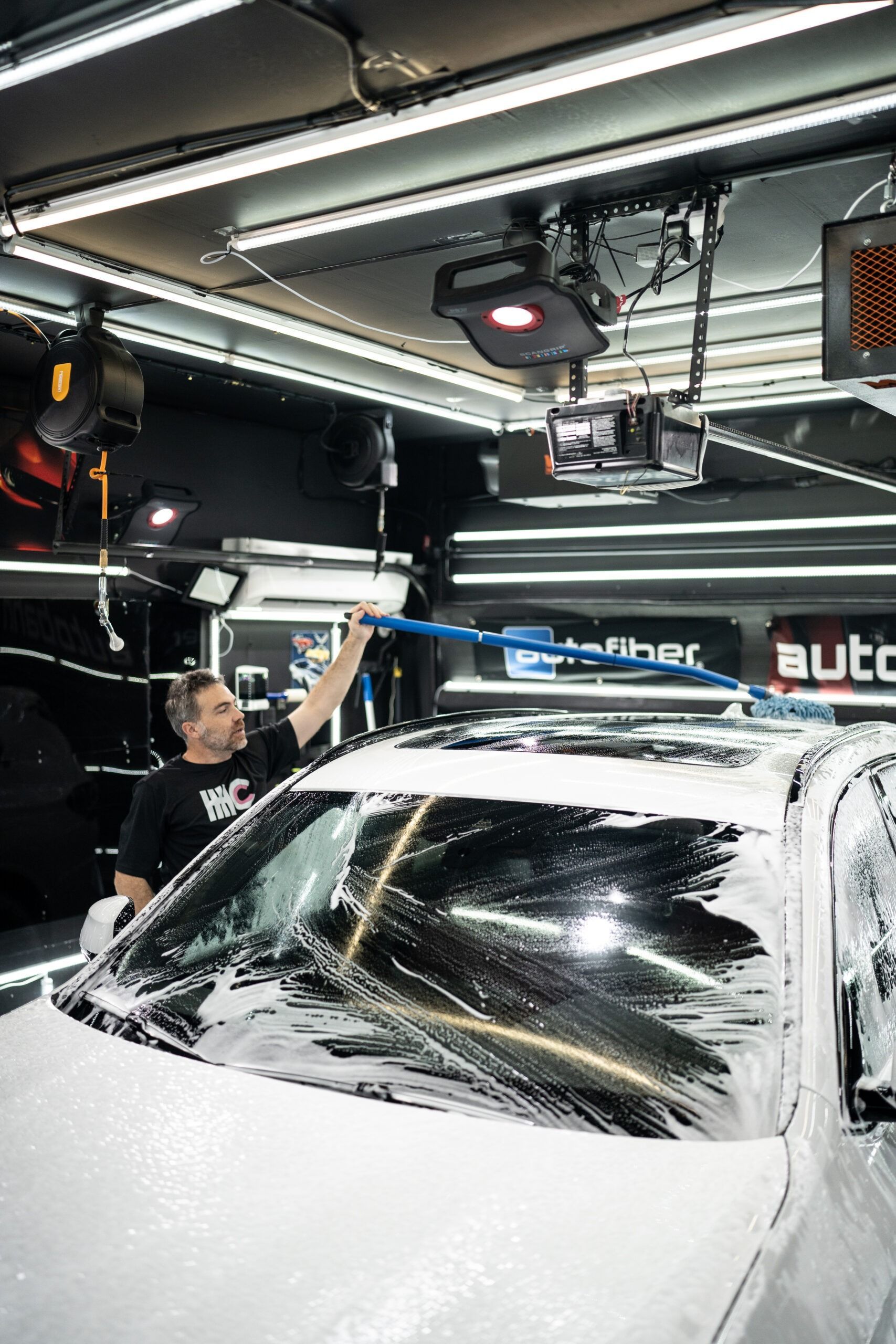 A man is washing a car in a garage.