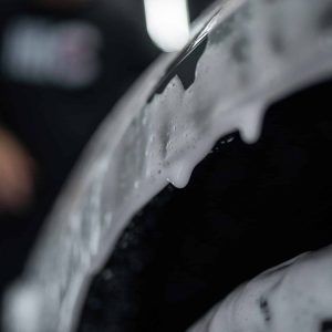 A close up of a person washing a car with soap and water.