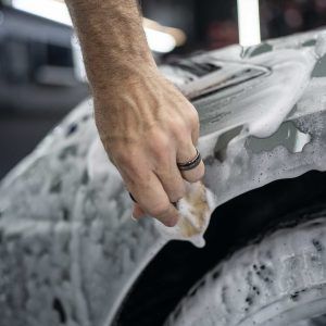 A person is washing a car with soap and water.