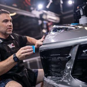 A man is working on the front of a car.