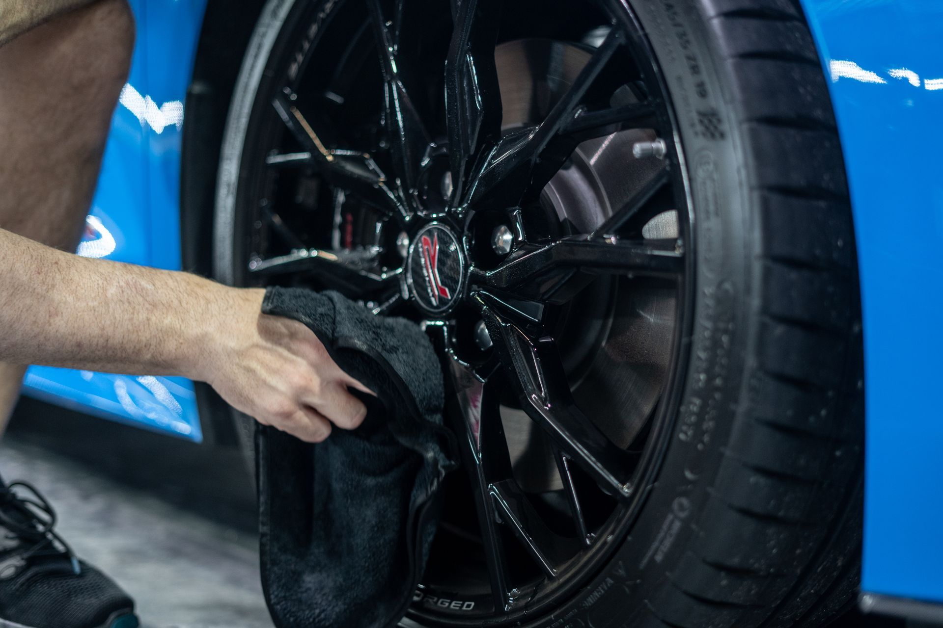 A person is cleaning a car wheel with a towel.