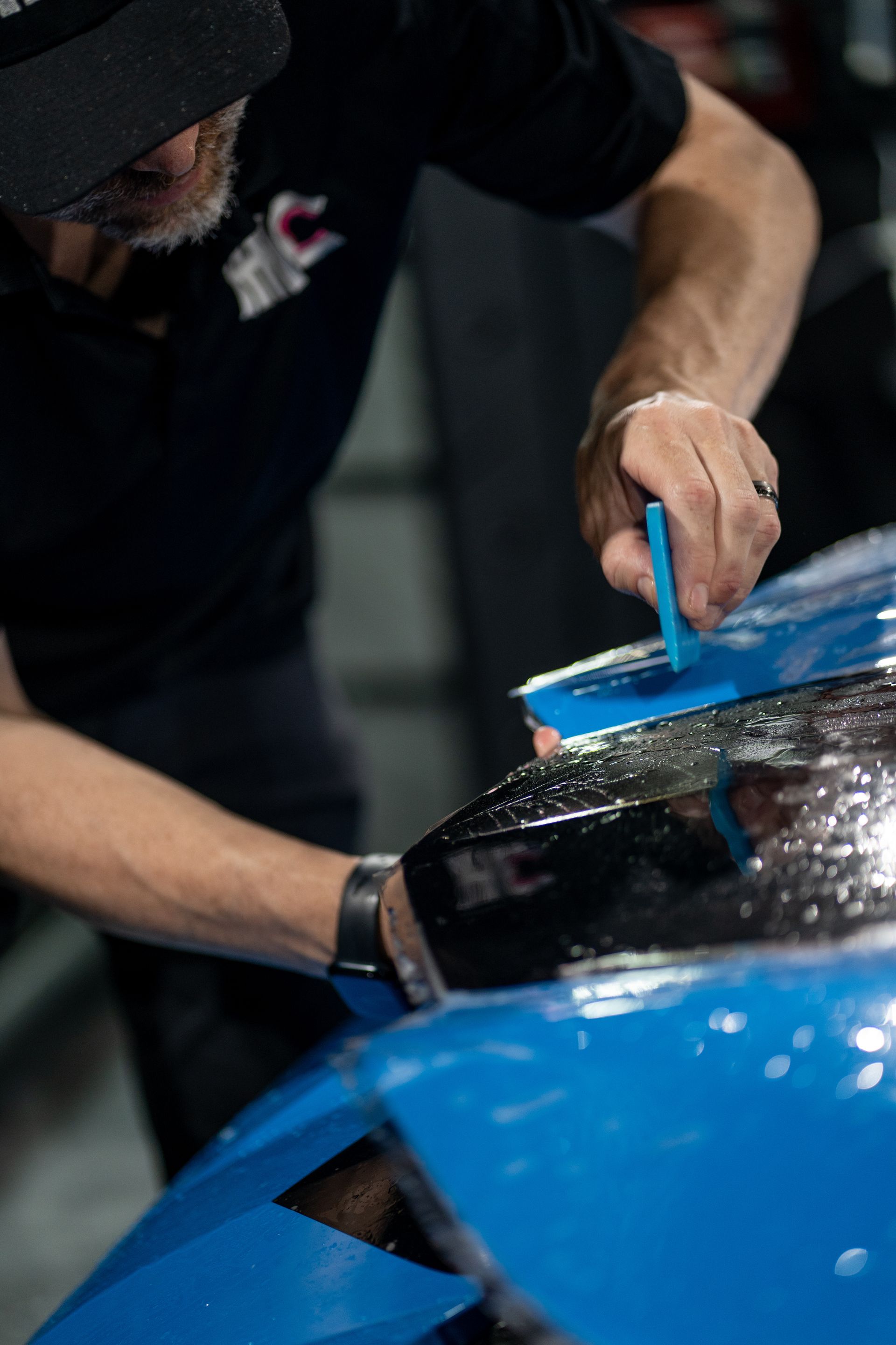 A man is working on a blue car in a garage.