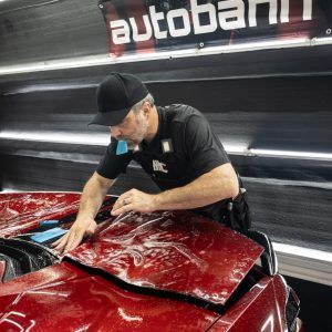 A man is working on a red car in a garage.