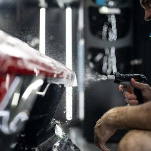A man is spraying water on a motorcycle.