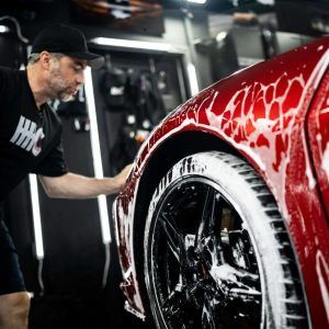A man is washing a red car in a garage.