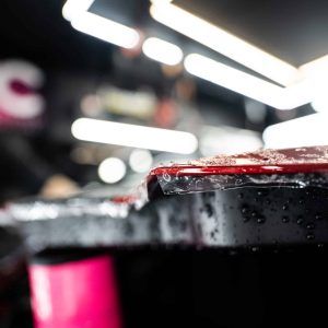 A close up of a red and black object with water drops on it.