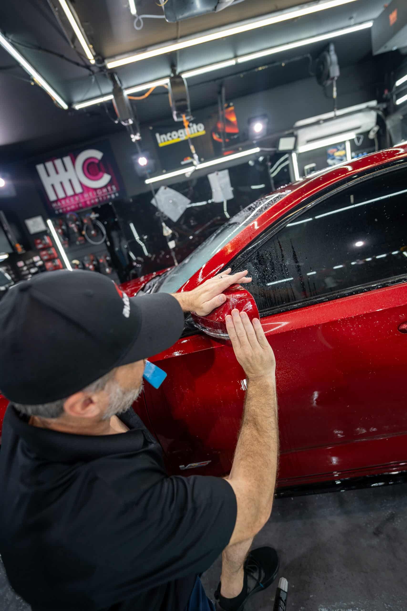 A man is working on a red car in a garage.