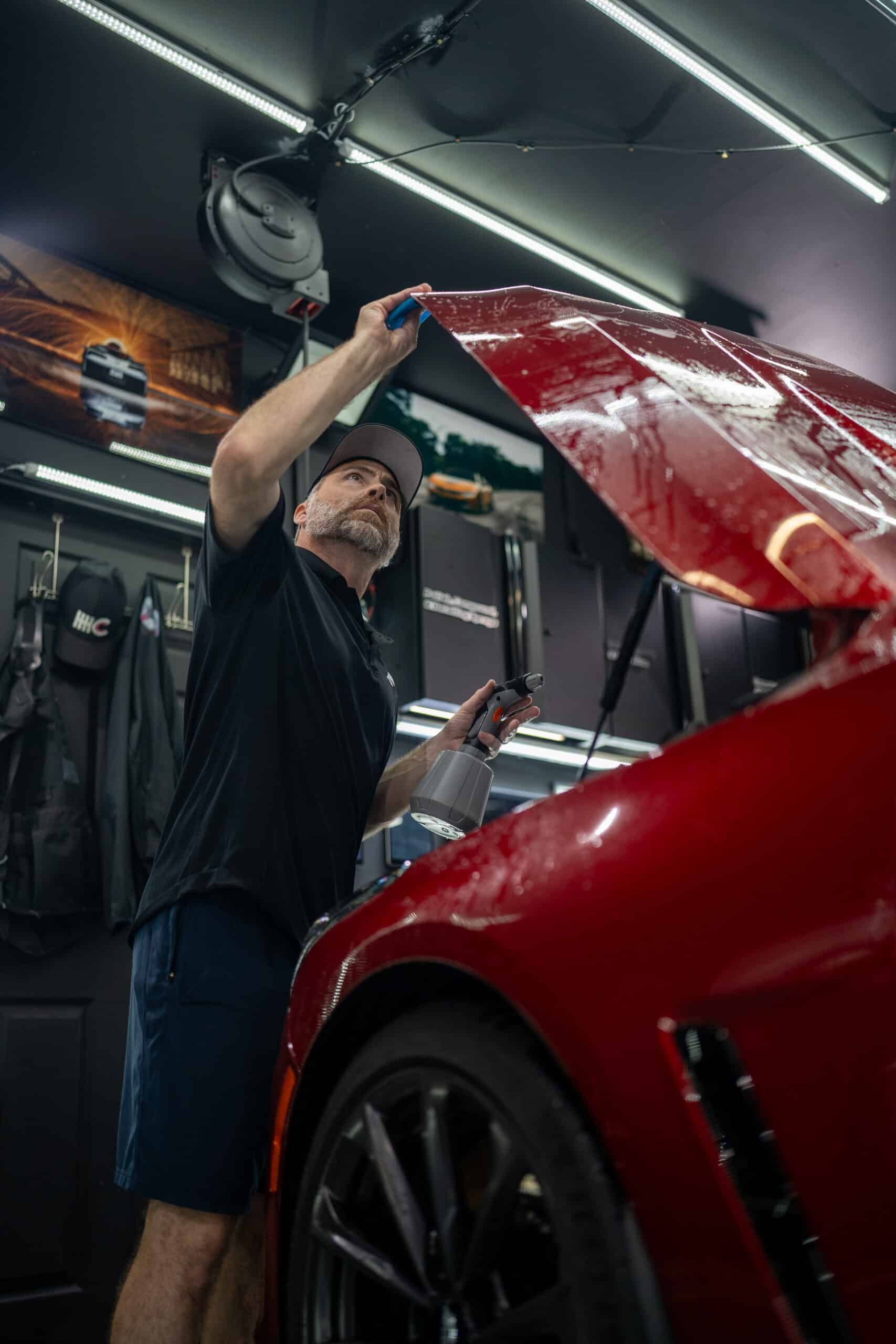 A man is working on a red car in a garage.