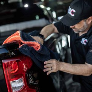 A man is cleaning the back of a truck with a towel.