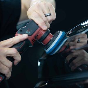 A person is polishing a car with a machine.