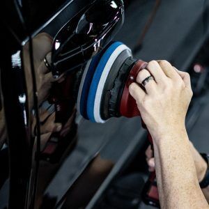 A person is polishing a car with a machine.
