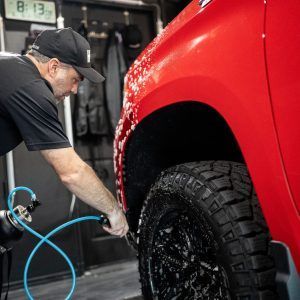 A man is working on a red truck in a garage.
