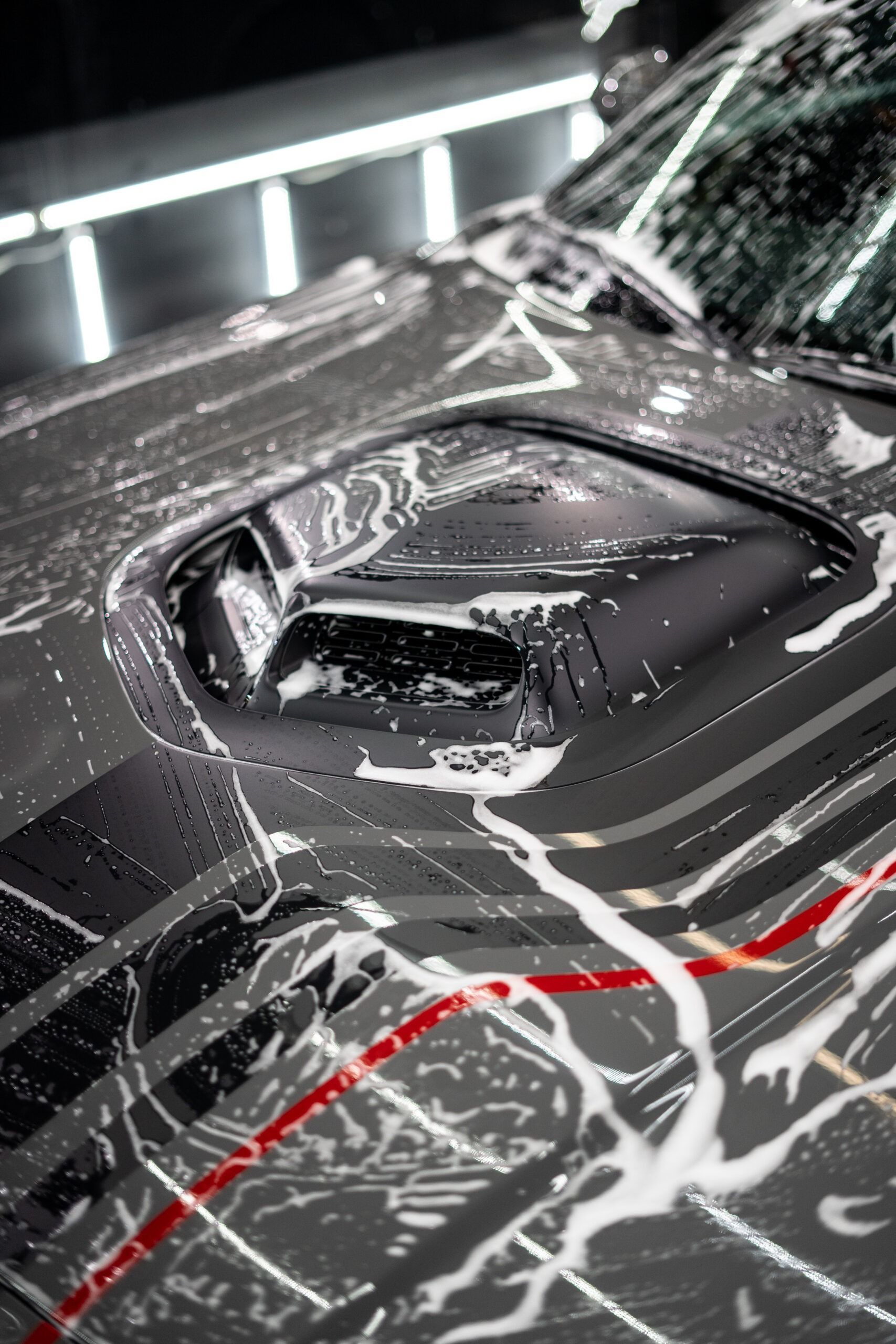 The hood of a black car is covered in soap.