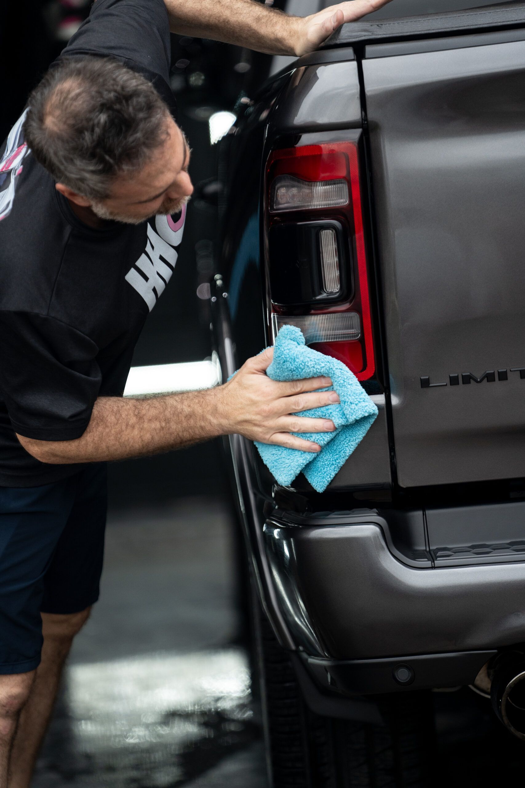 A man is cleaning the back of a truck with a towel.