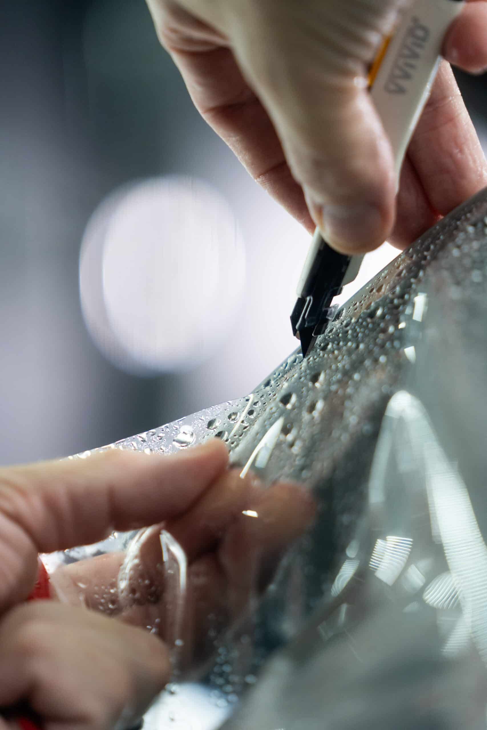 A person is cutting a piece of plastic with a pair of scissors.