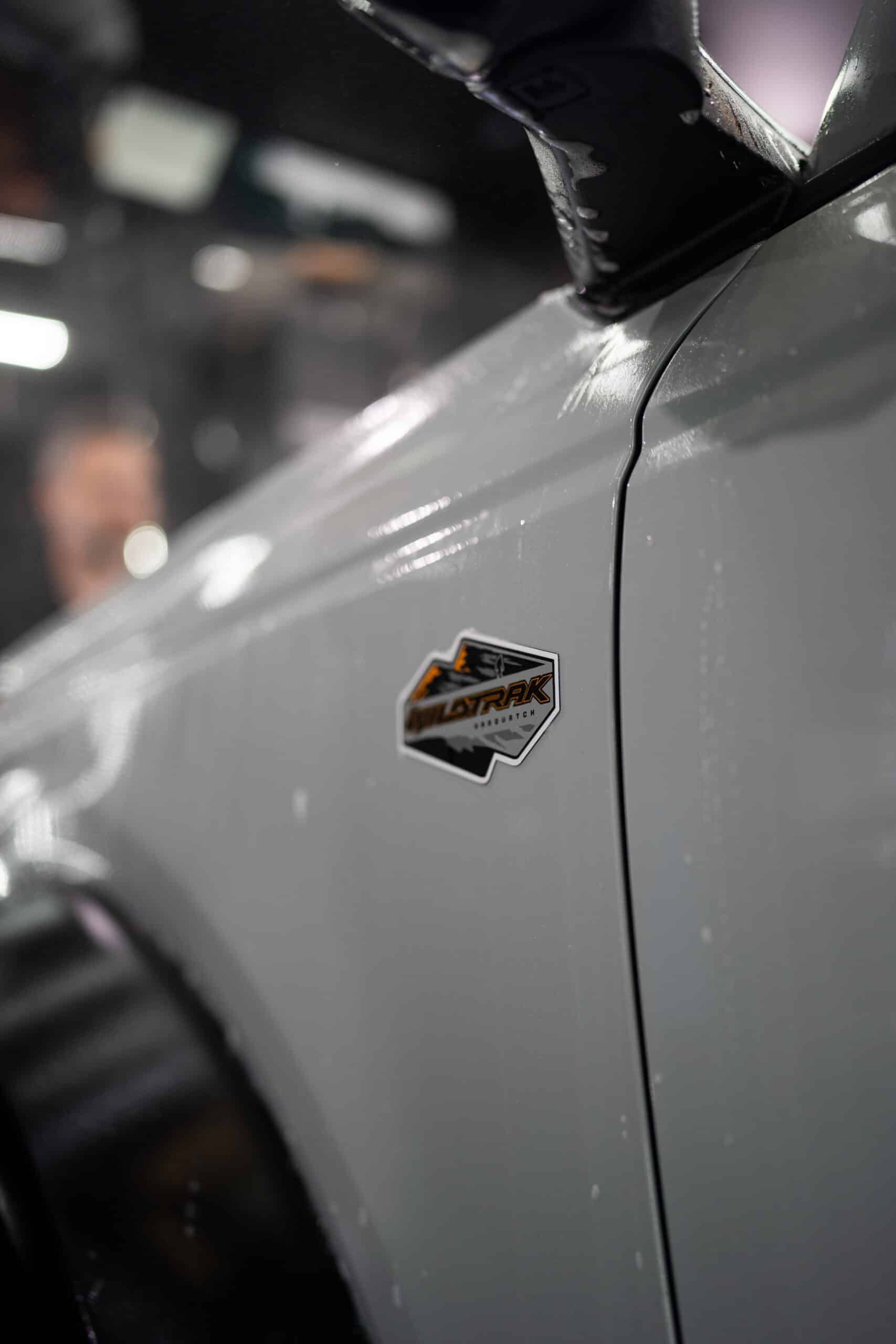 A close up of the side of a white car with a badge on it.