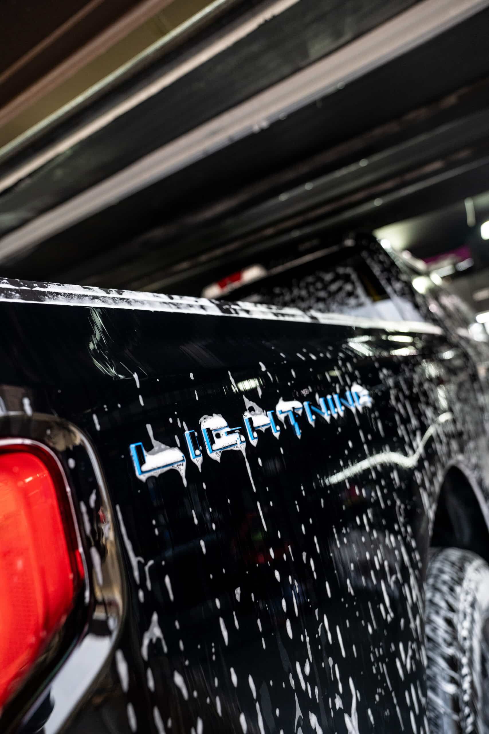 A black car is being washed with soap and water