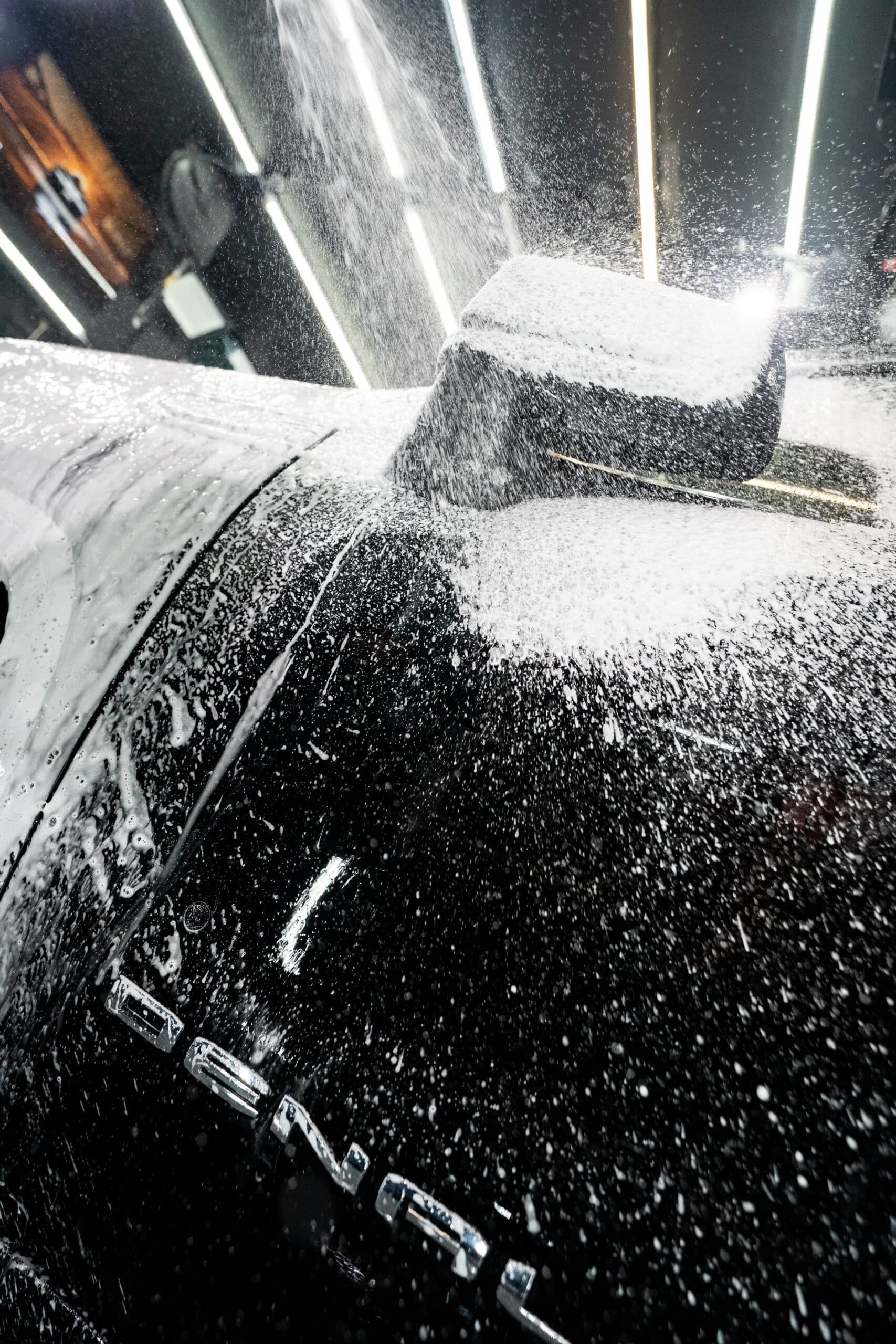 A car is being cleaned with a sponge and foam.