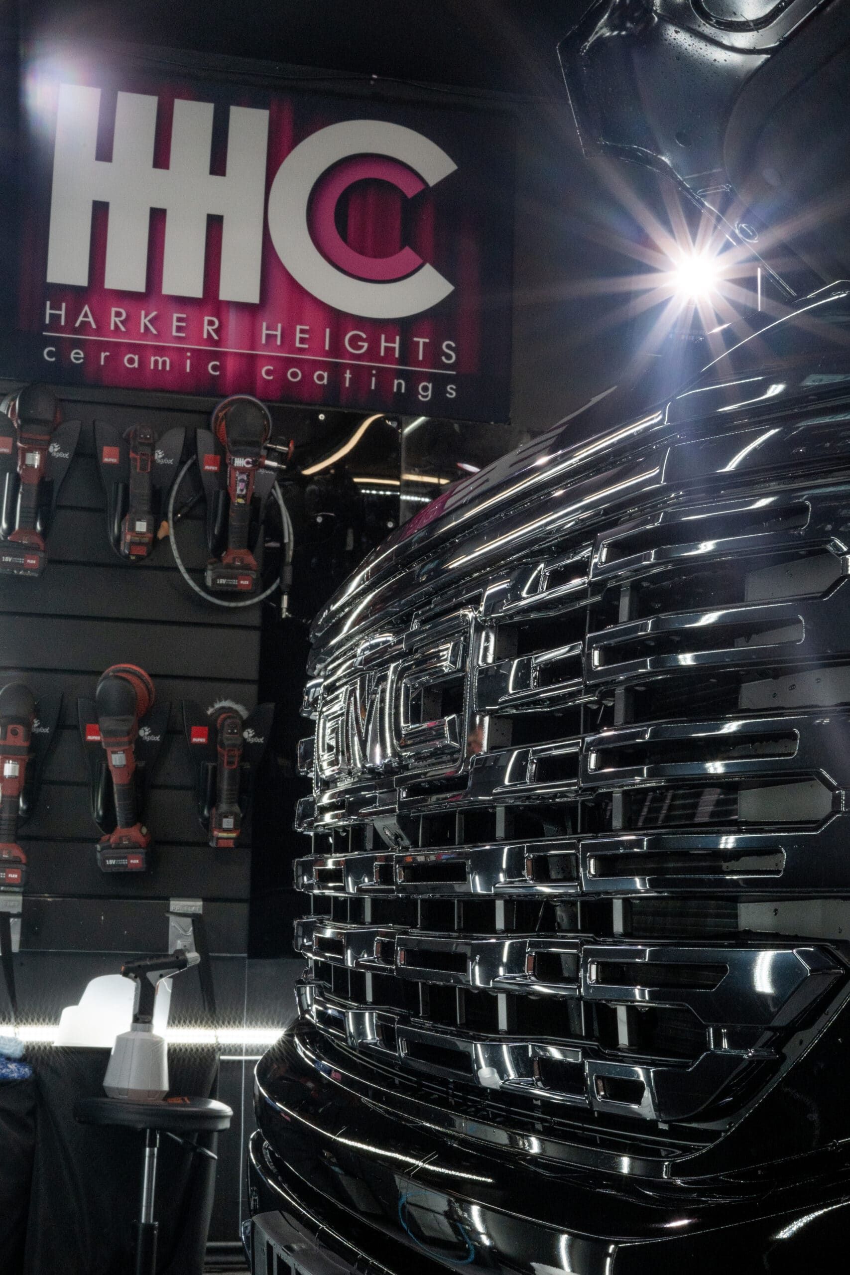A black truck is parked in front of a sign that says hhc