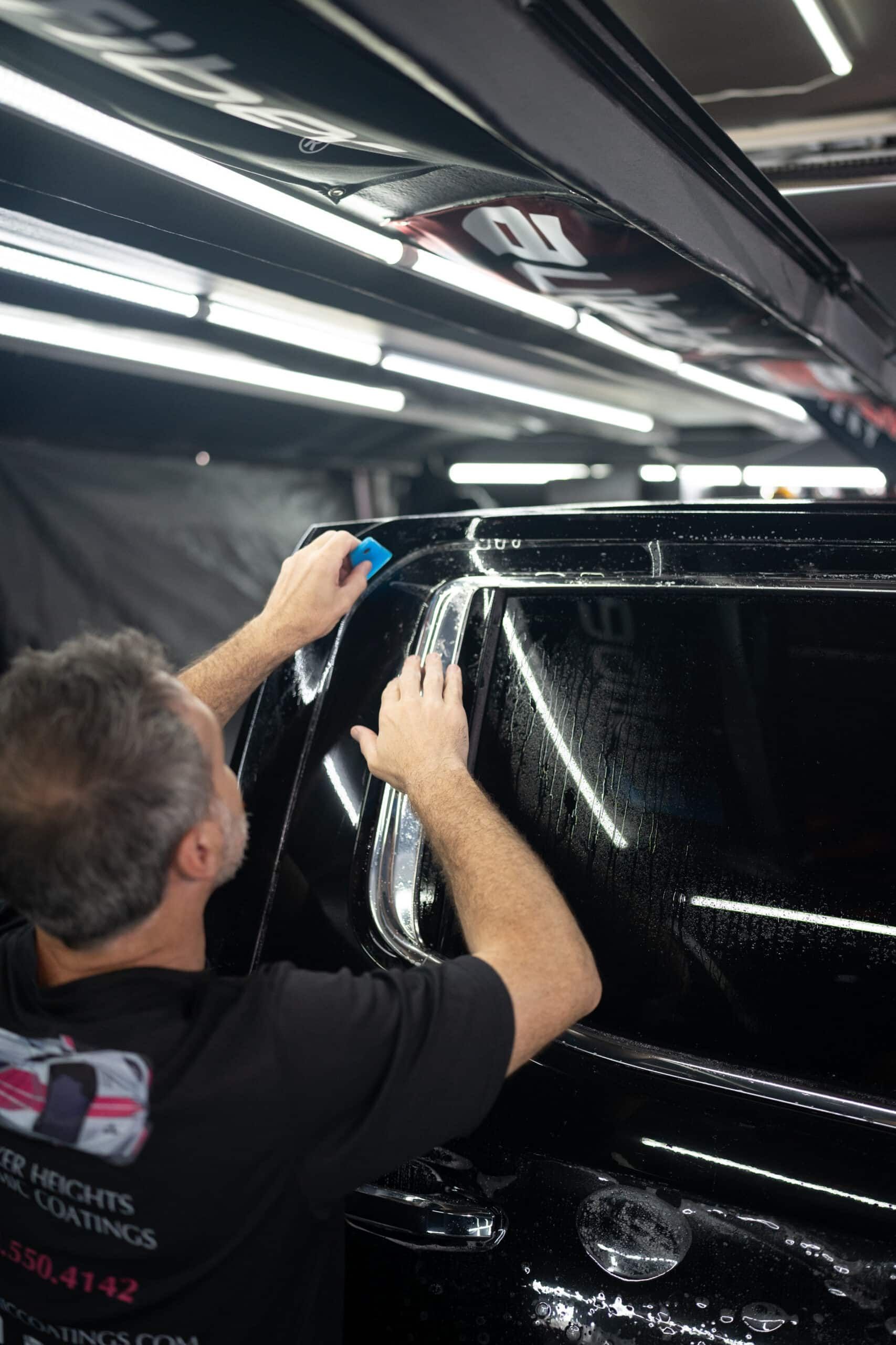 A man is working on a black car in a garage.