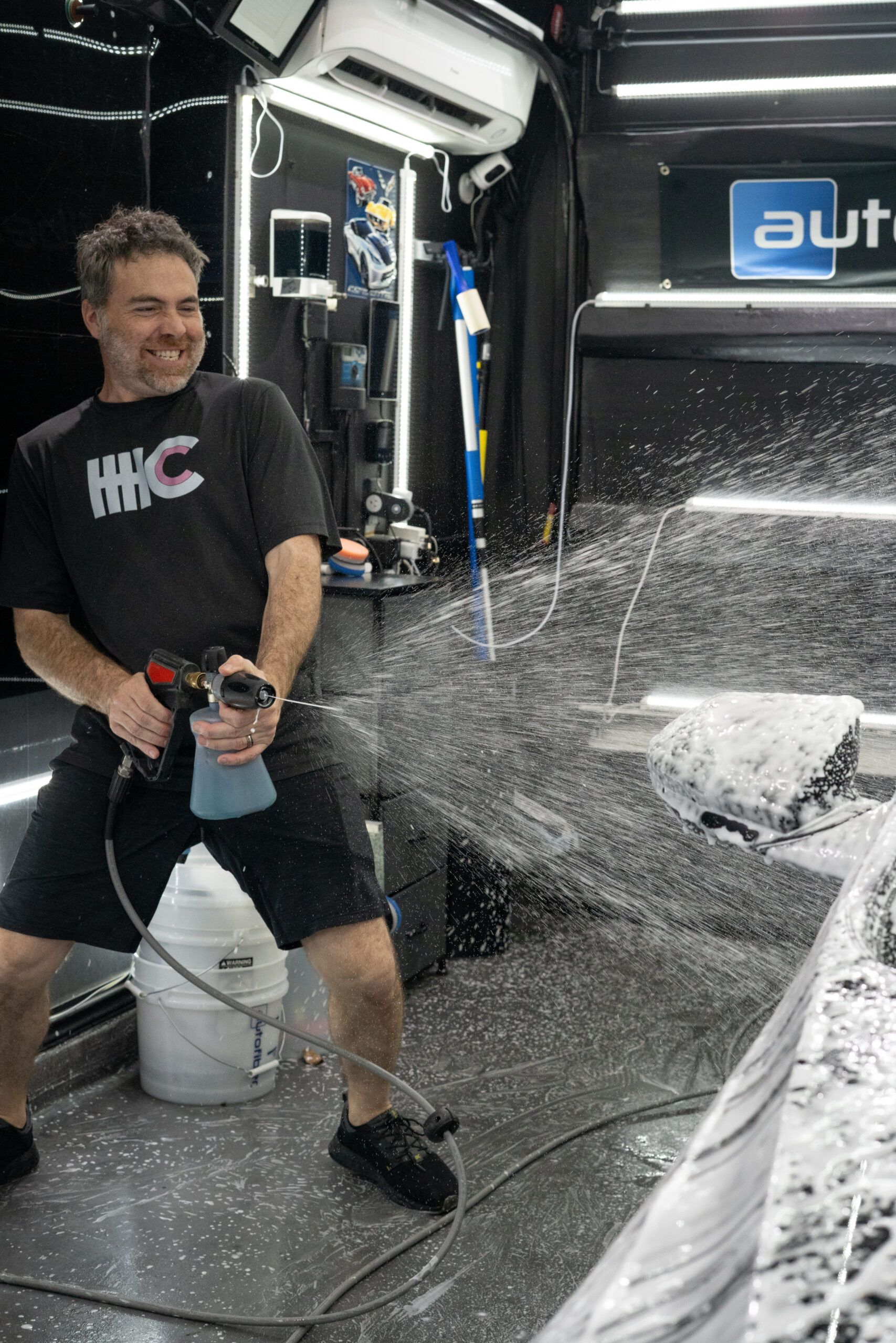A man is sitting on the floor holding a spray bottle.