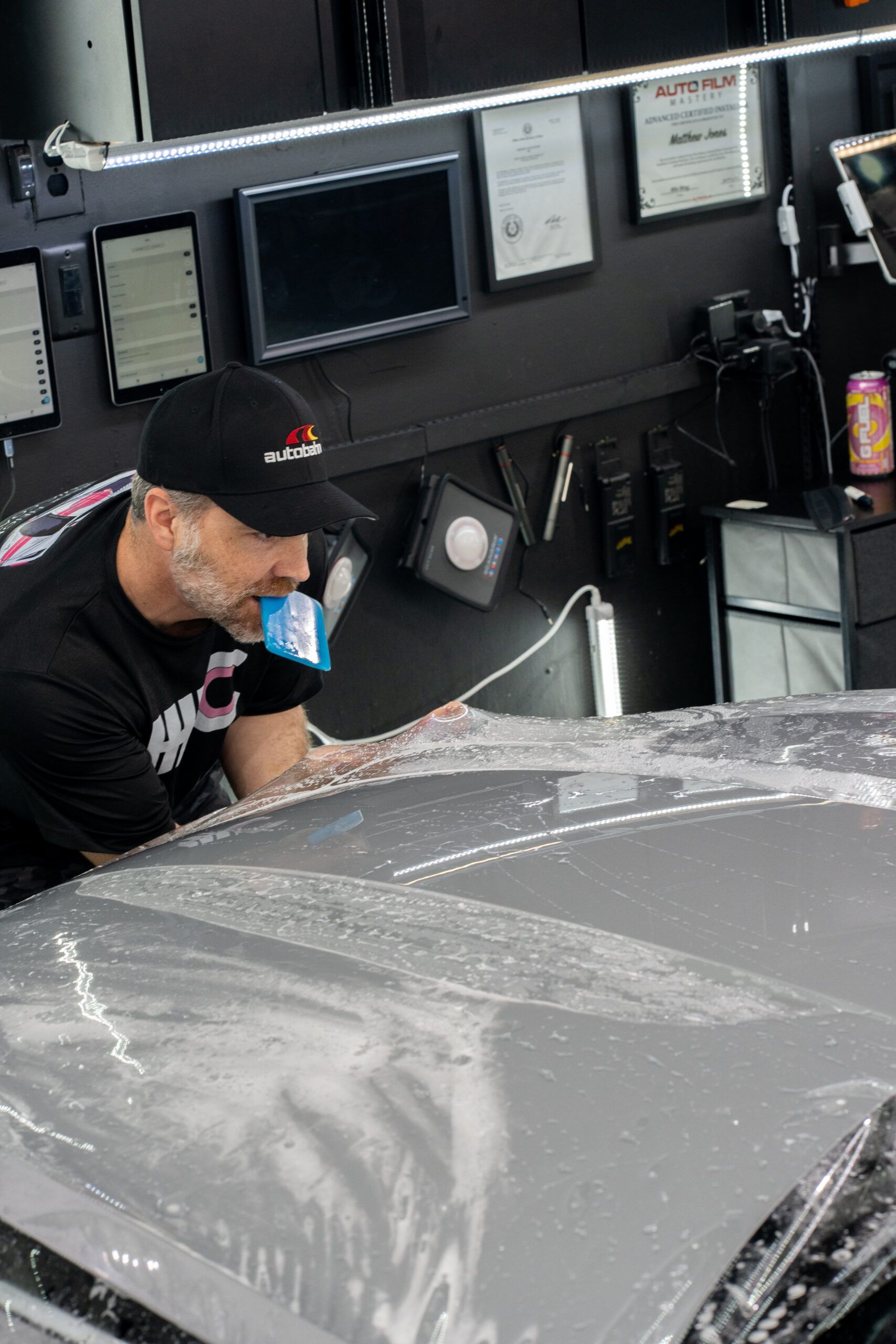 A man is wrapping a car with plastic wrap in a garage.