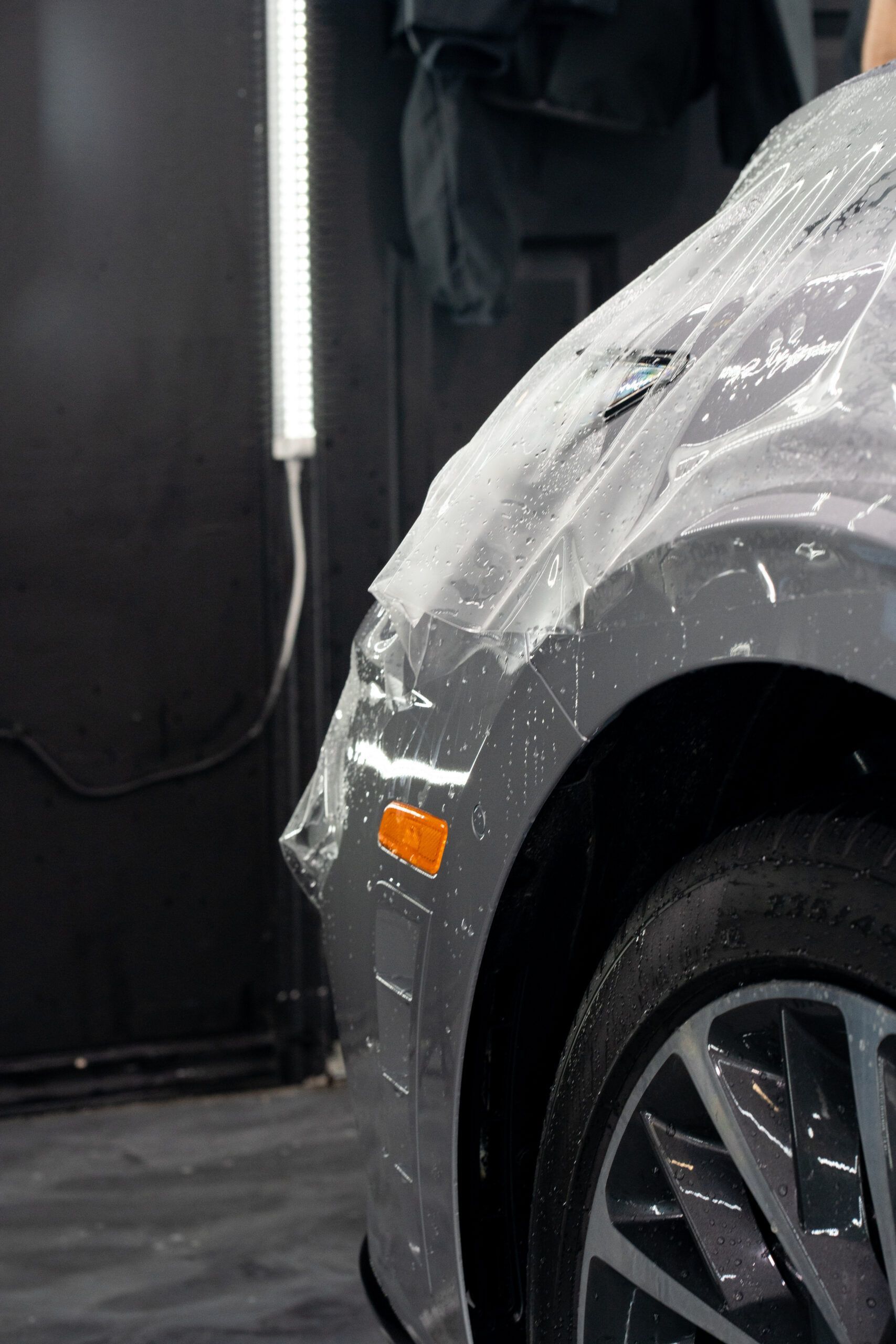 A person is wrapping a car with plastic wrap.