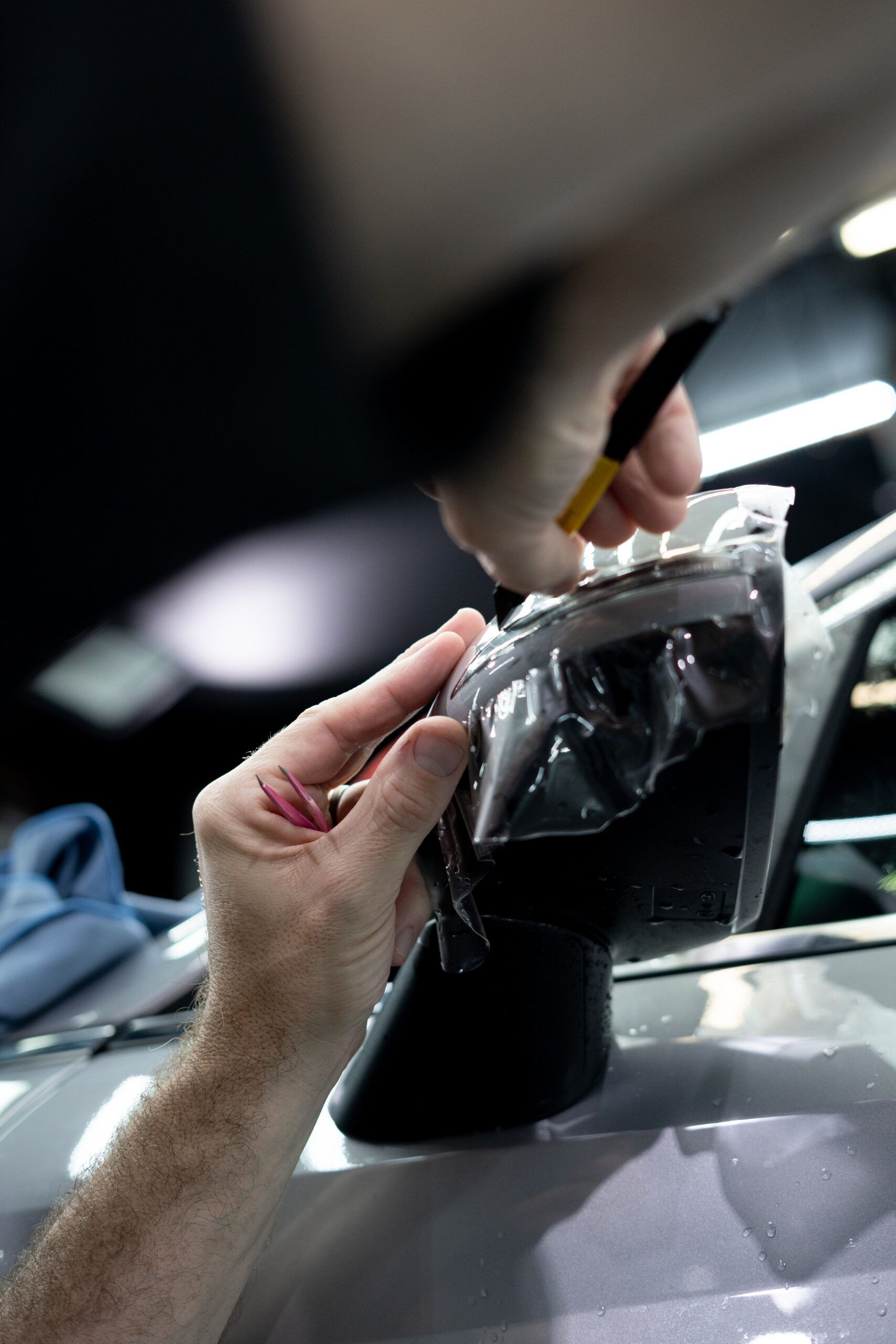 A person is putting a piece of plastic on a car window.