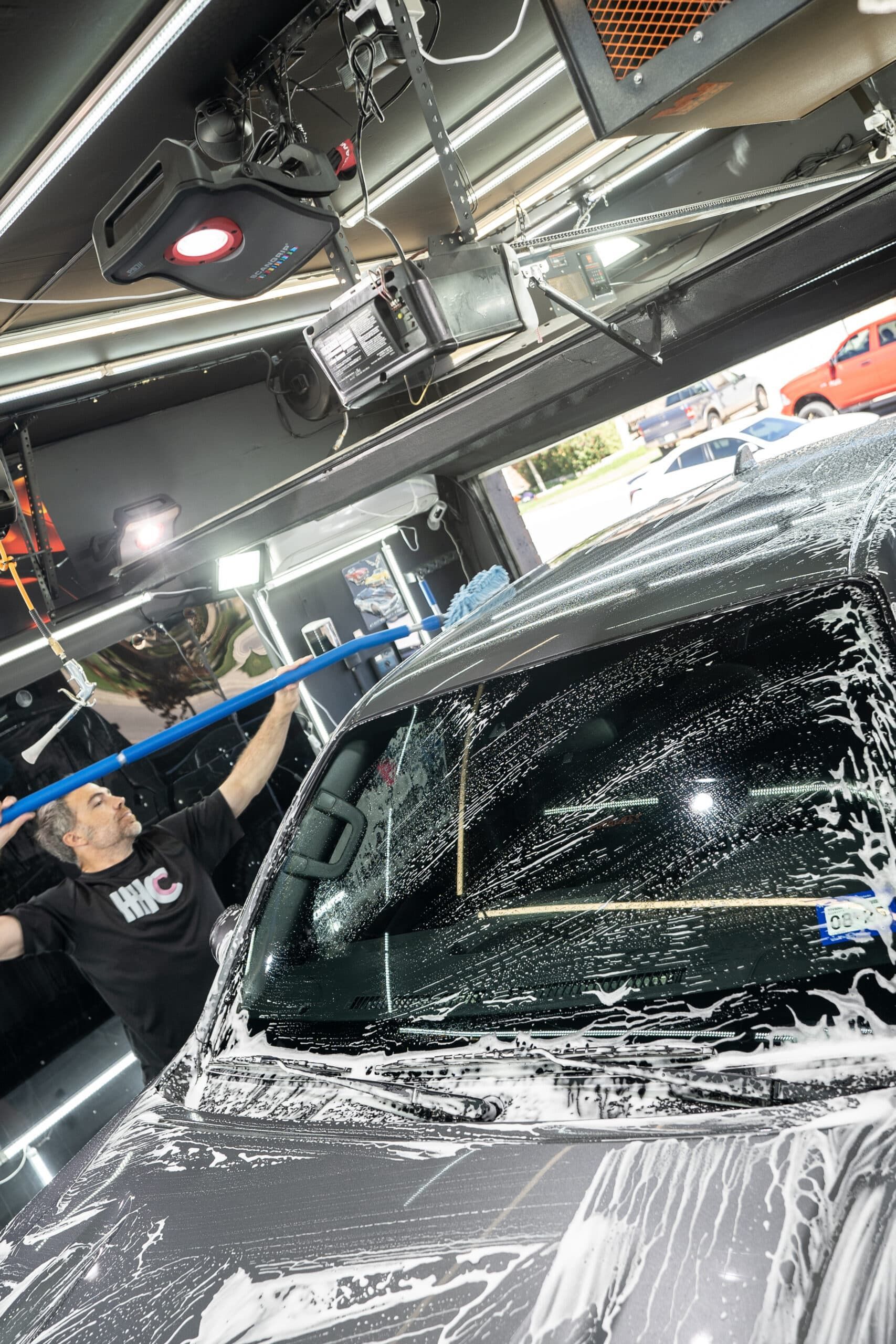 A man is washing a car with a hose in a garage.