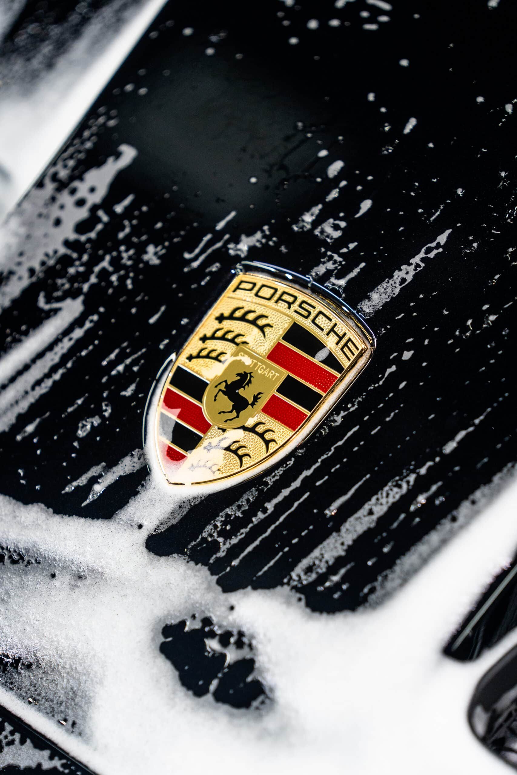 A close up of a porsche logo on a black car
