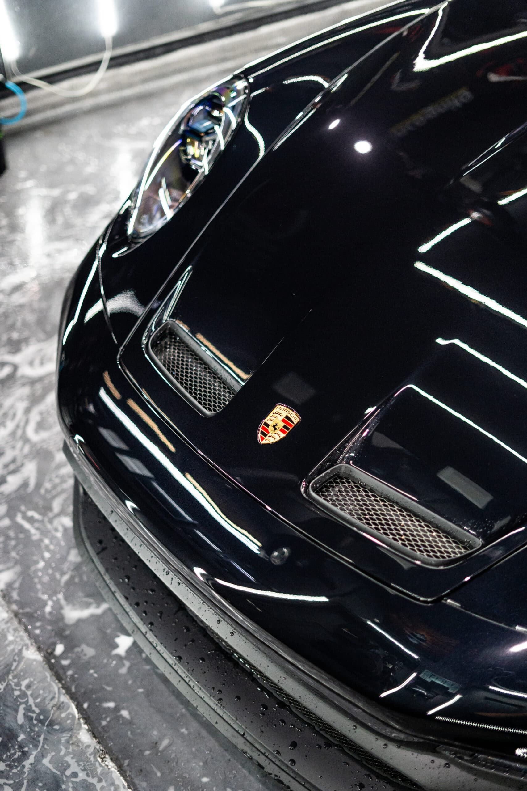 A black porsche 911 is parked in a garage.