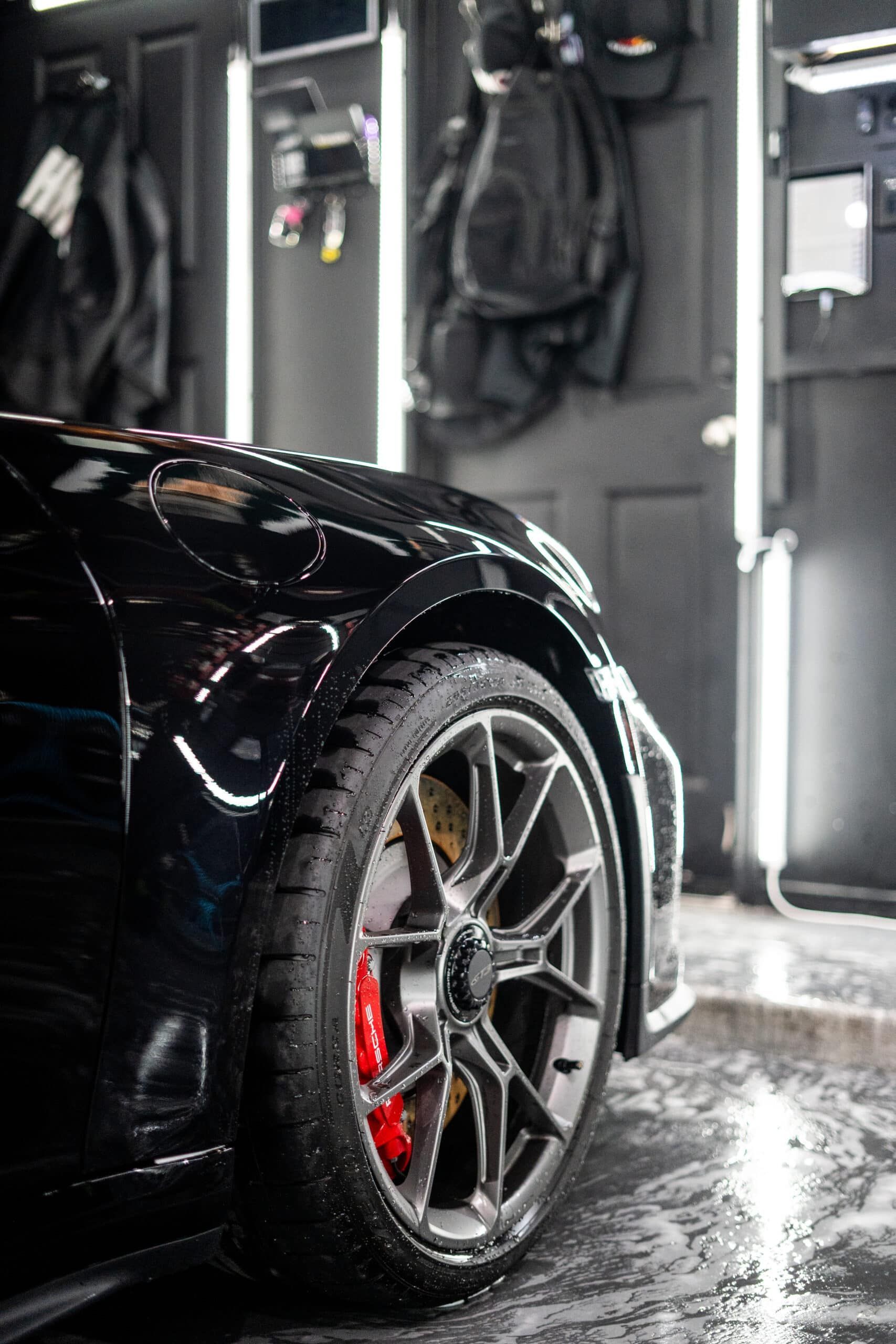 A black car with red brake calipers is parked in a garage.