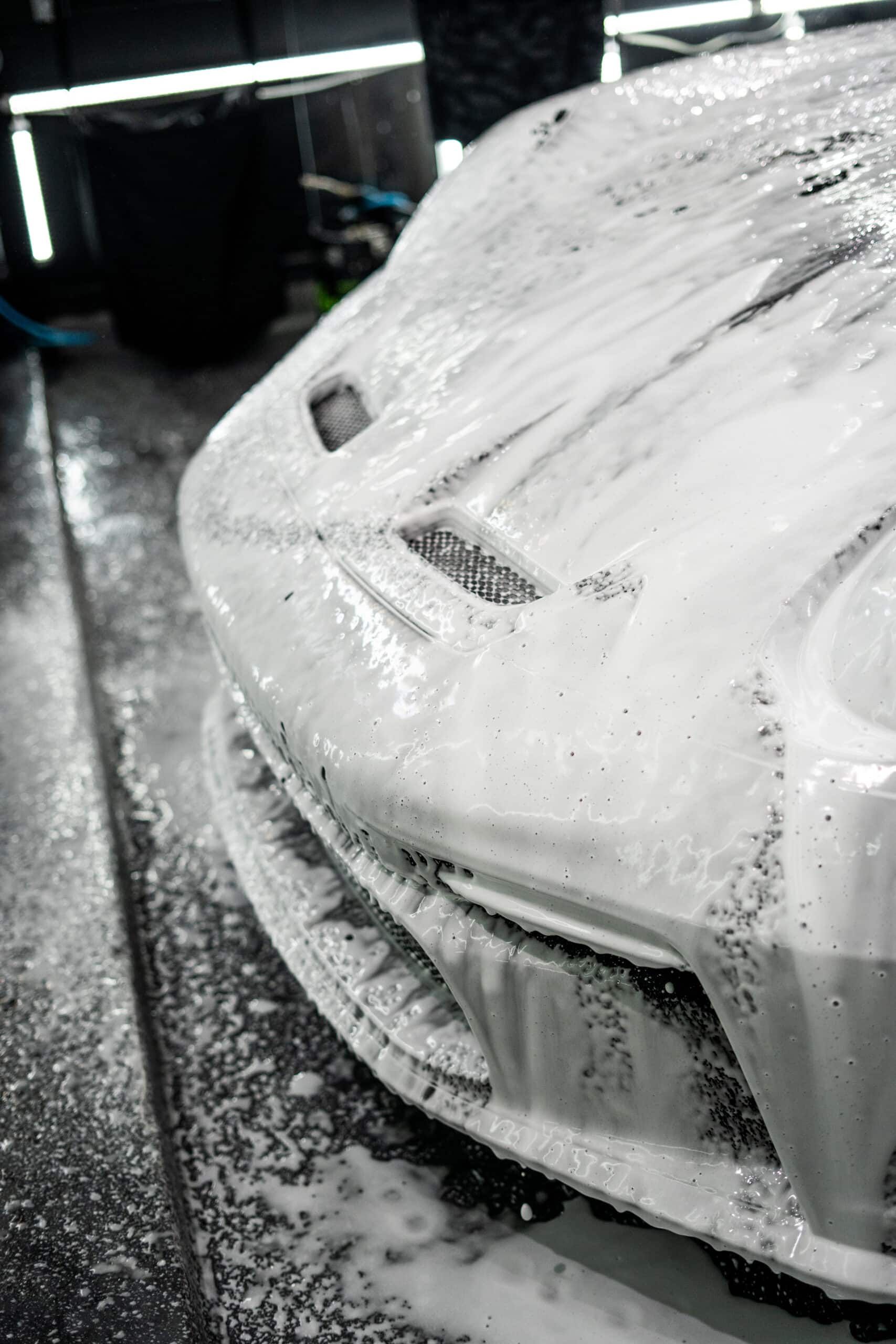 A black and white photo of a car covered in foam.