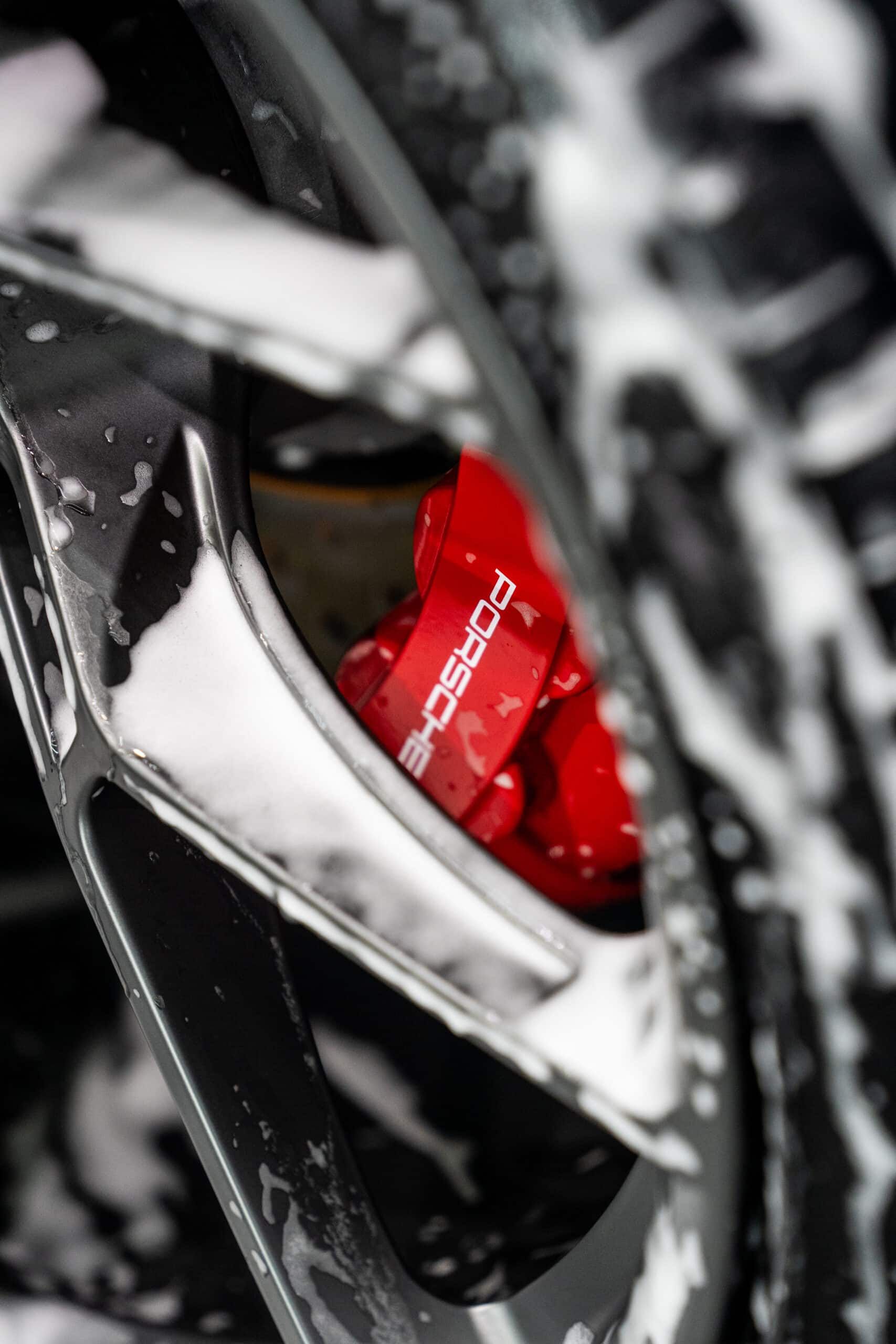 A close up of a car wheel with a red brake caliper.