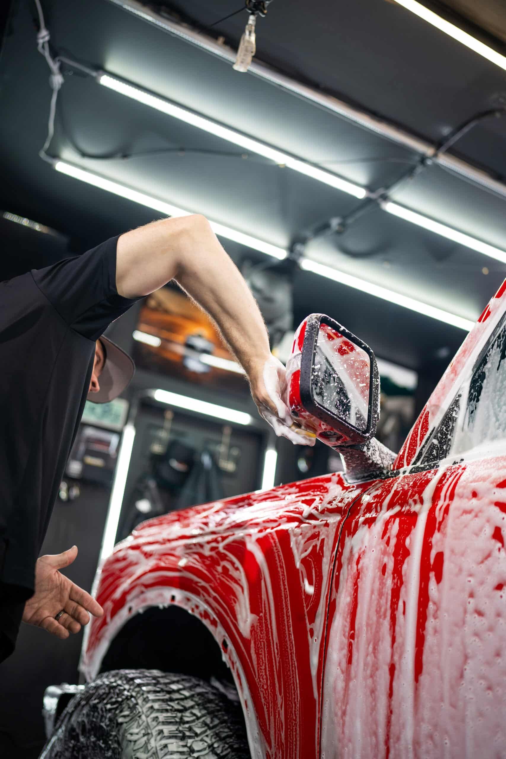 A man is washing a red truck in a garage.