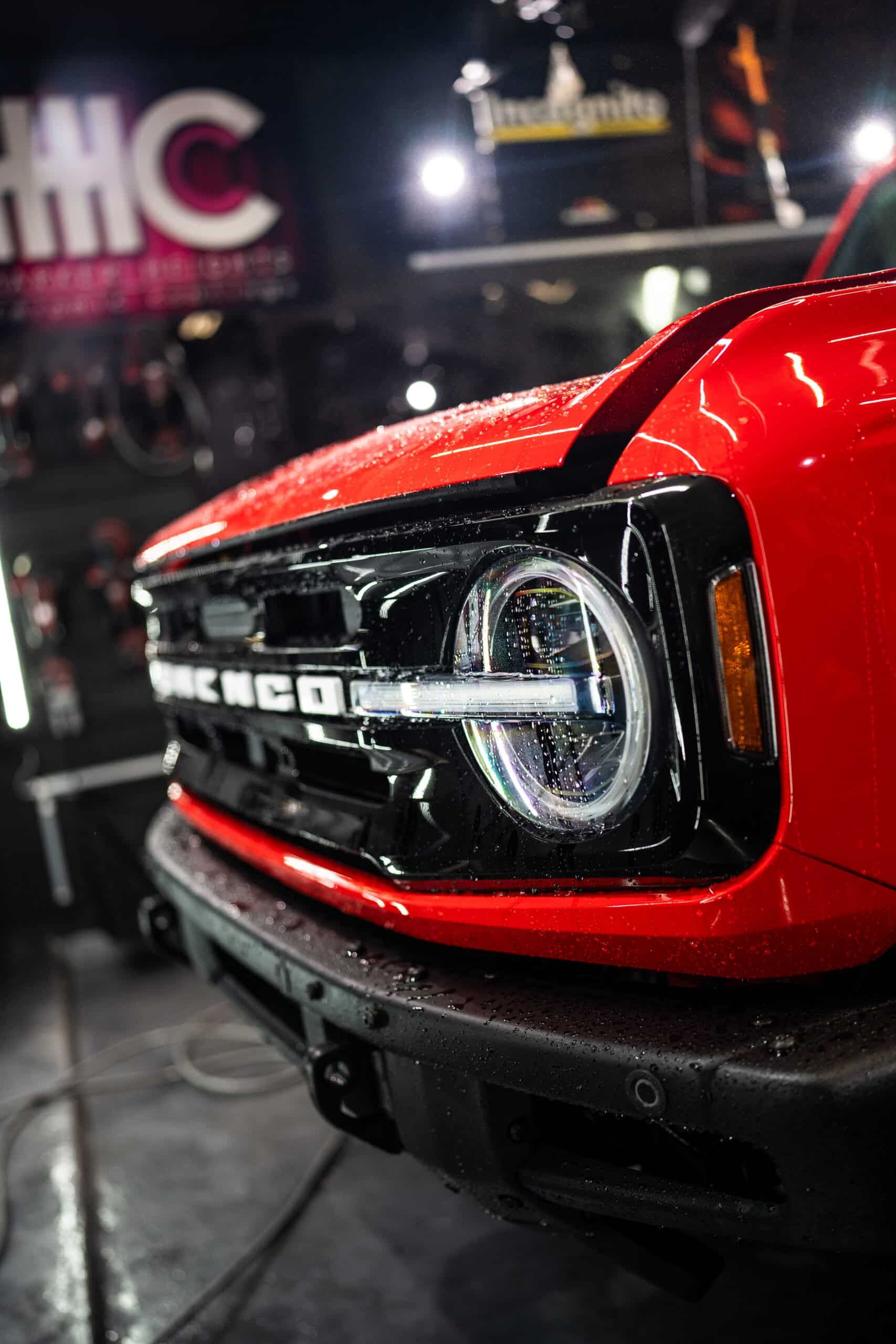 A red ford bronco is parked in a garage.