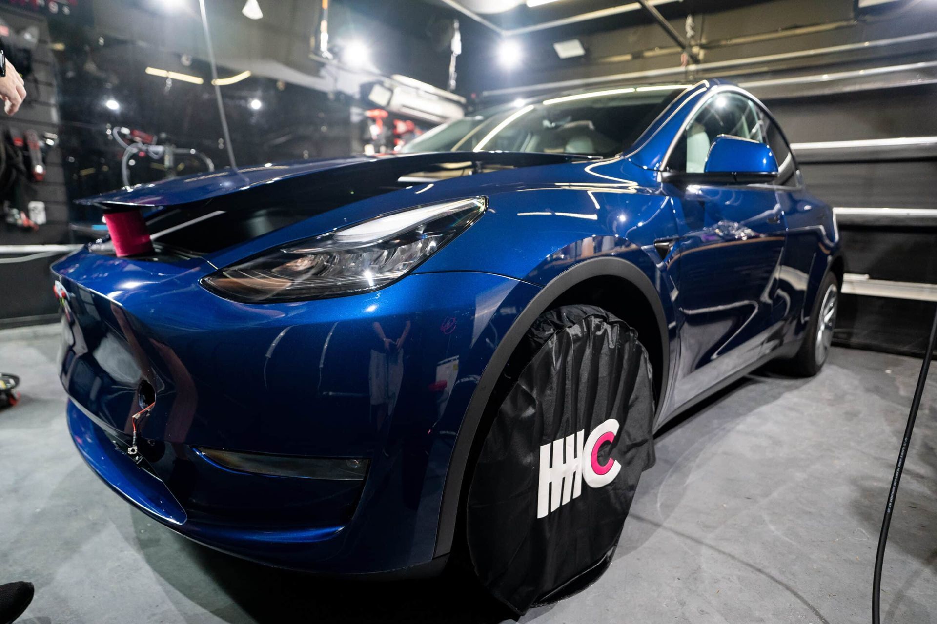 A blue tesla model y is parked in a garage.