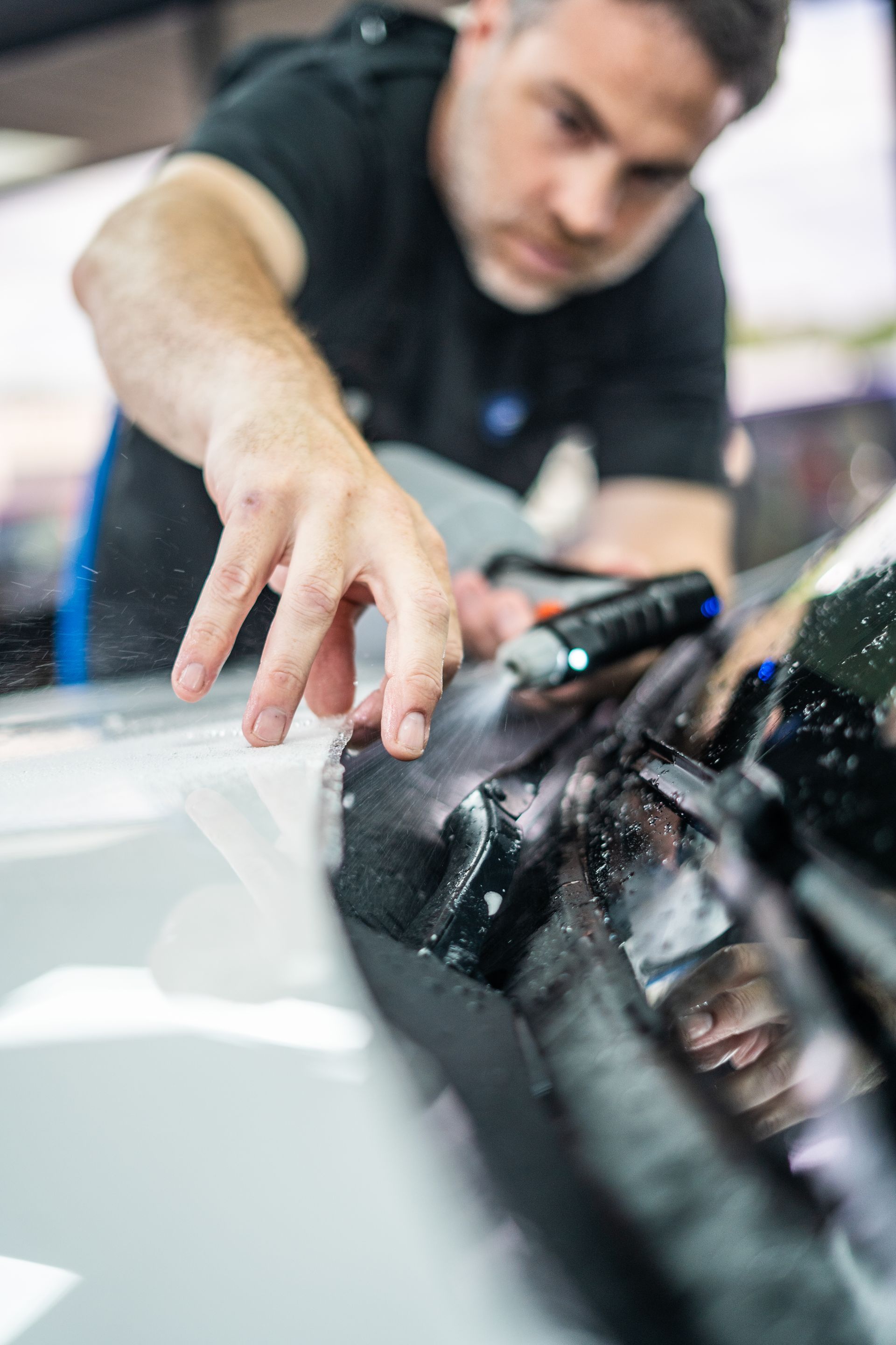 A black car is being cleaned in a garage.