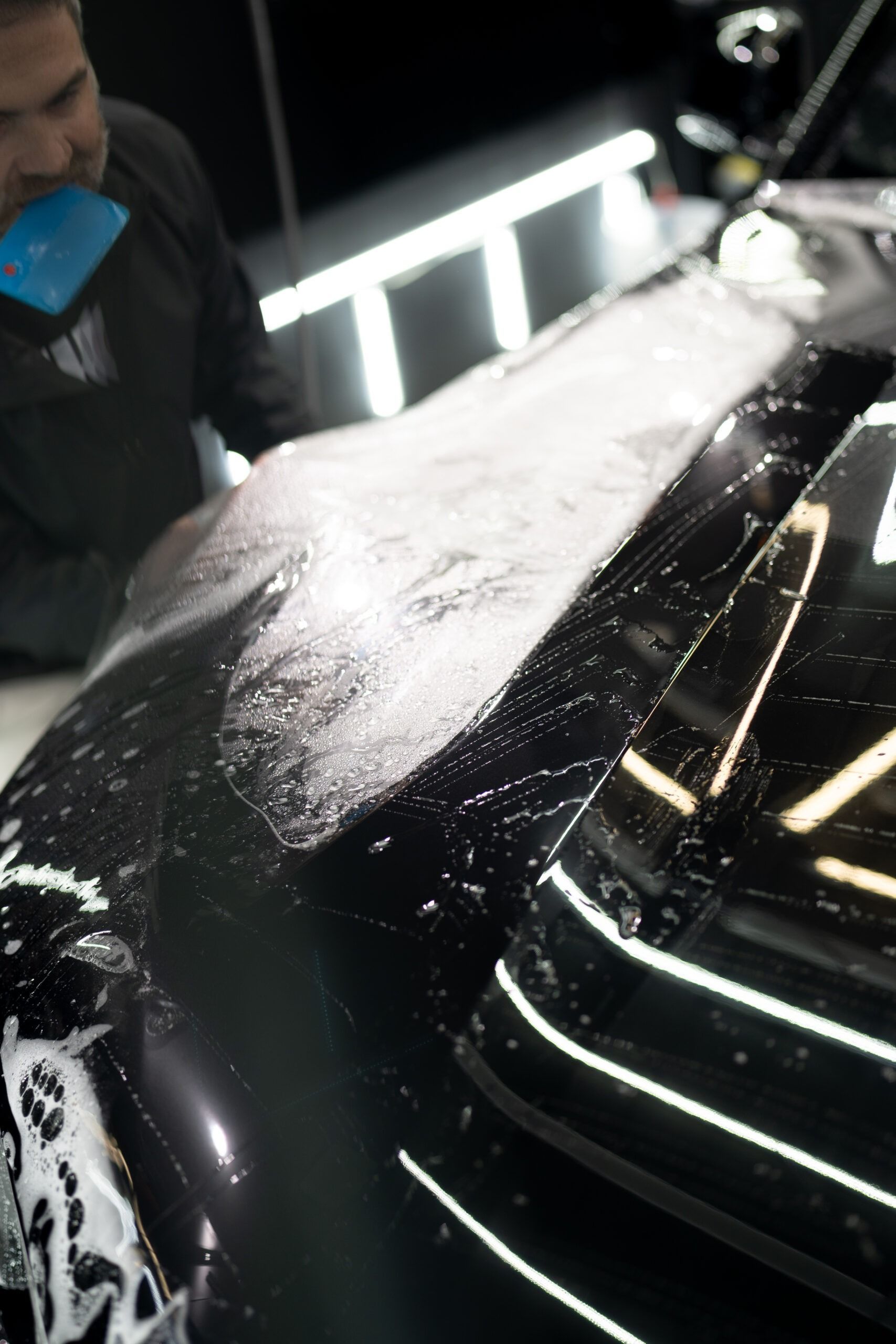 A man is washing the hood of a black car