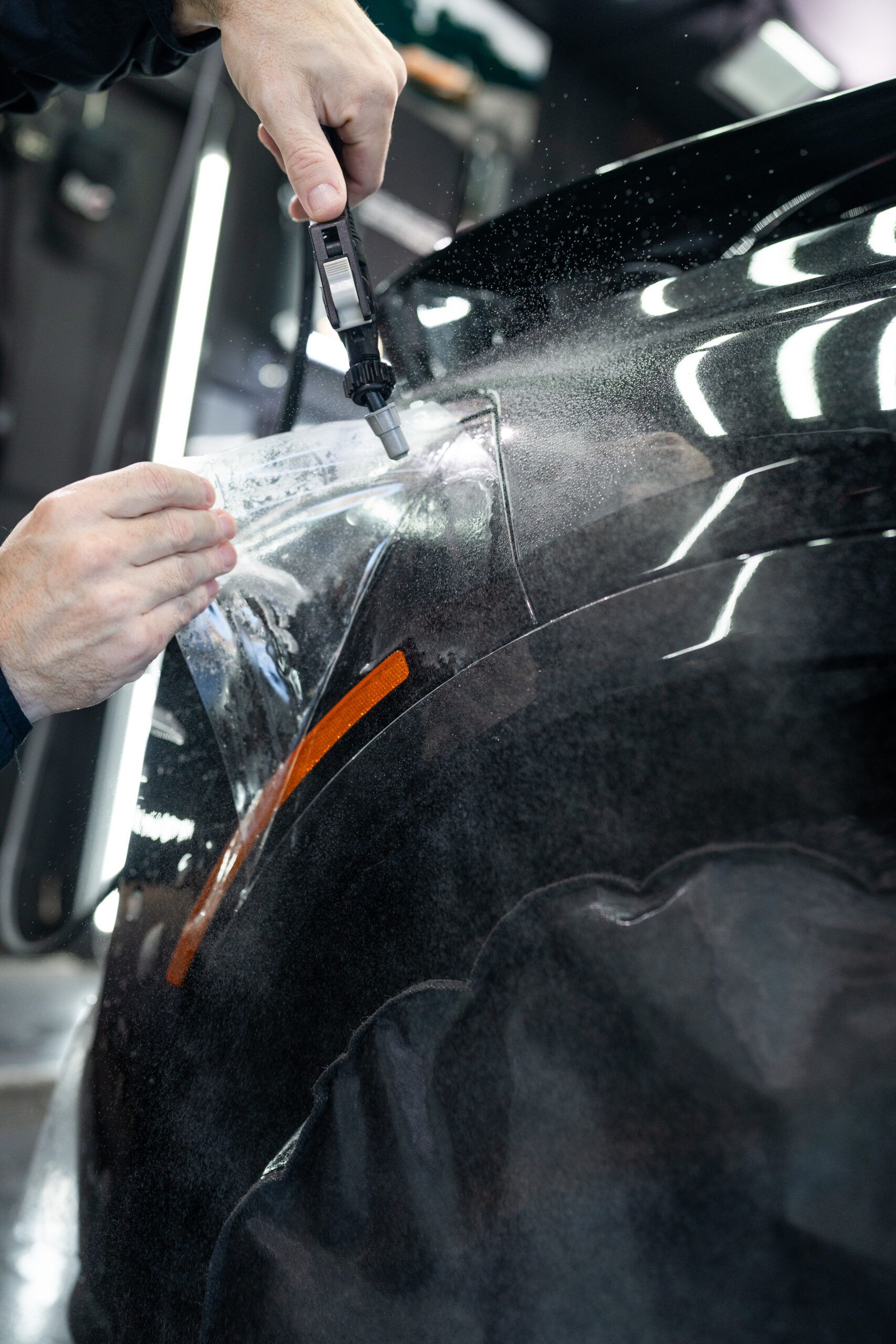 A person is wrapping a car with a piece of plastic.