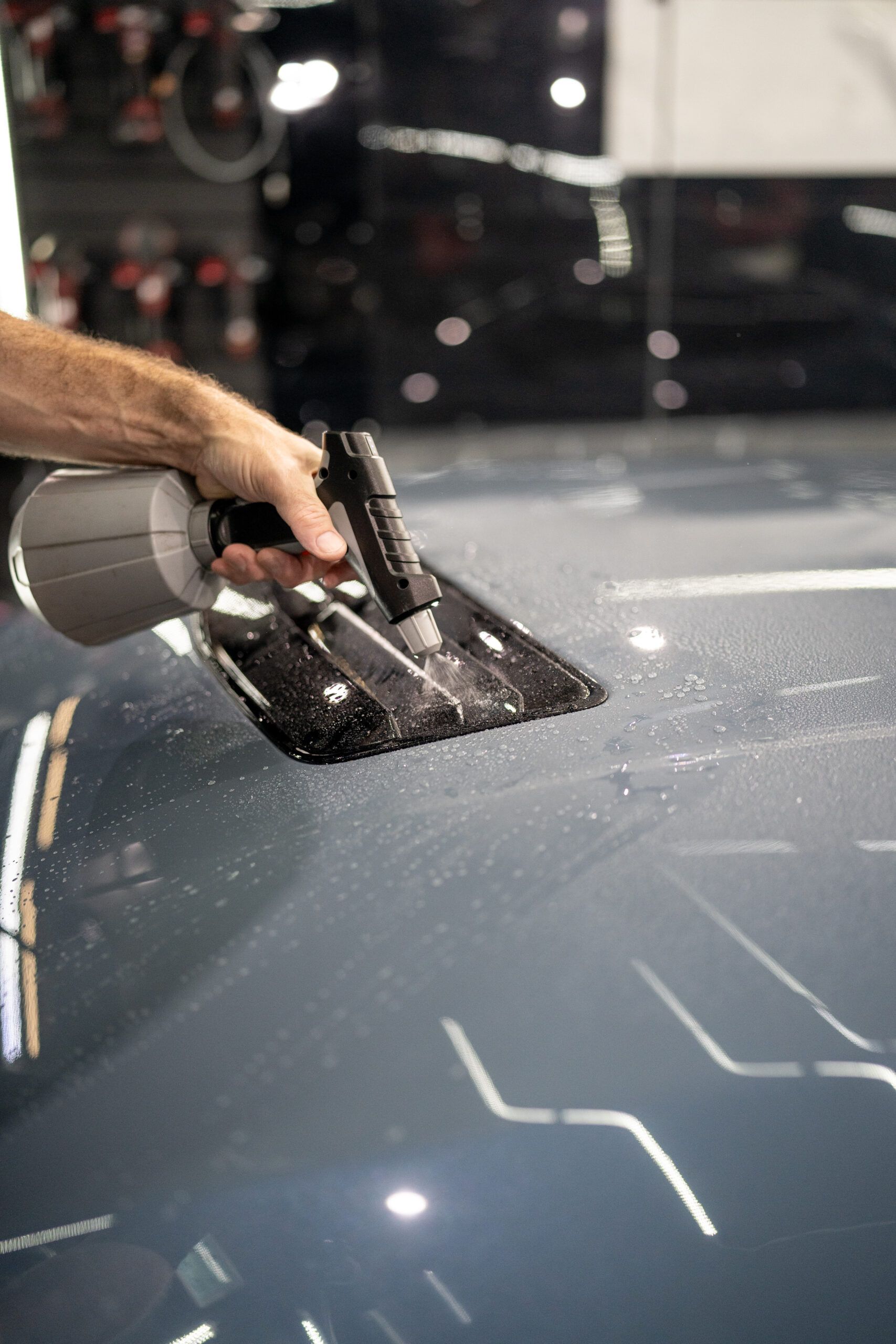 A person is cleaning the roof of a car with a spray bottle.