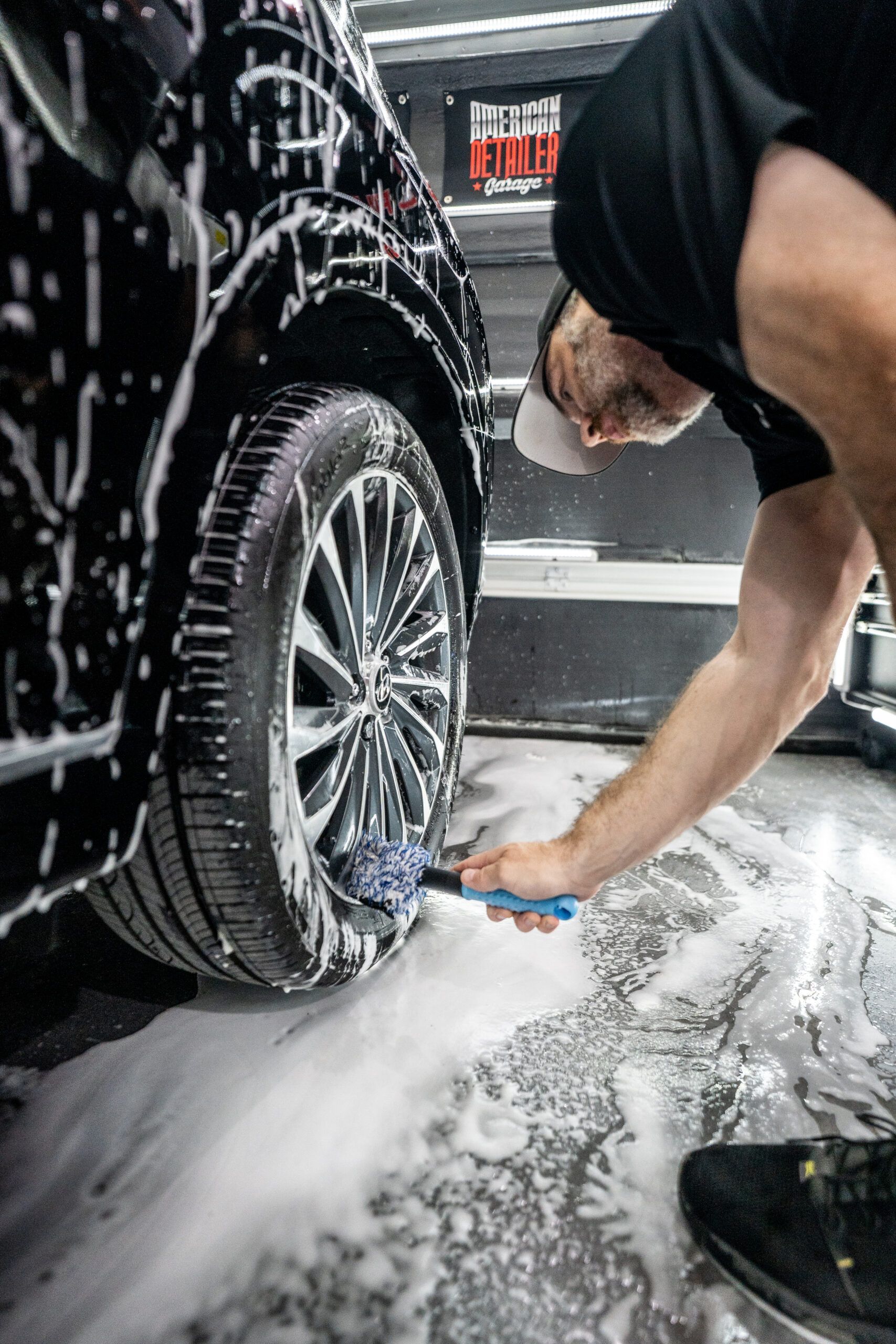 A man is washing a car with a brush.