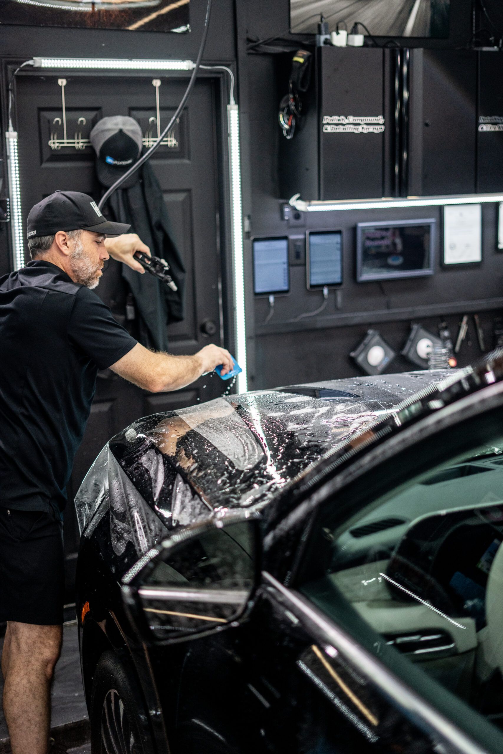 A man is wrapping a car with plastic wrap in a garage.
