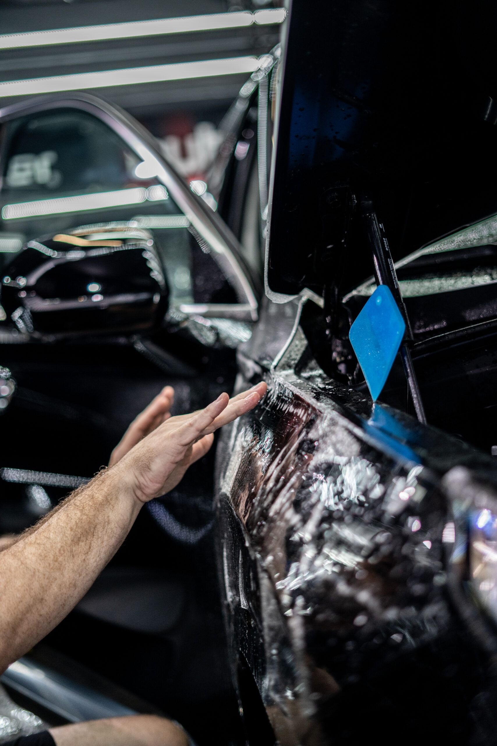 A man is wrapping a car with plastic wrap.