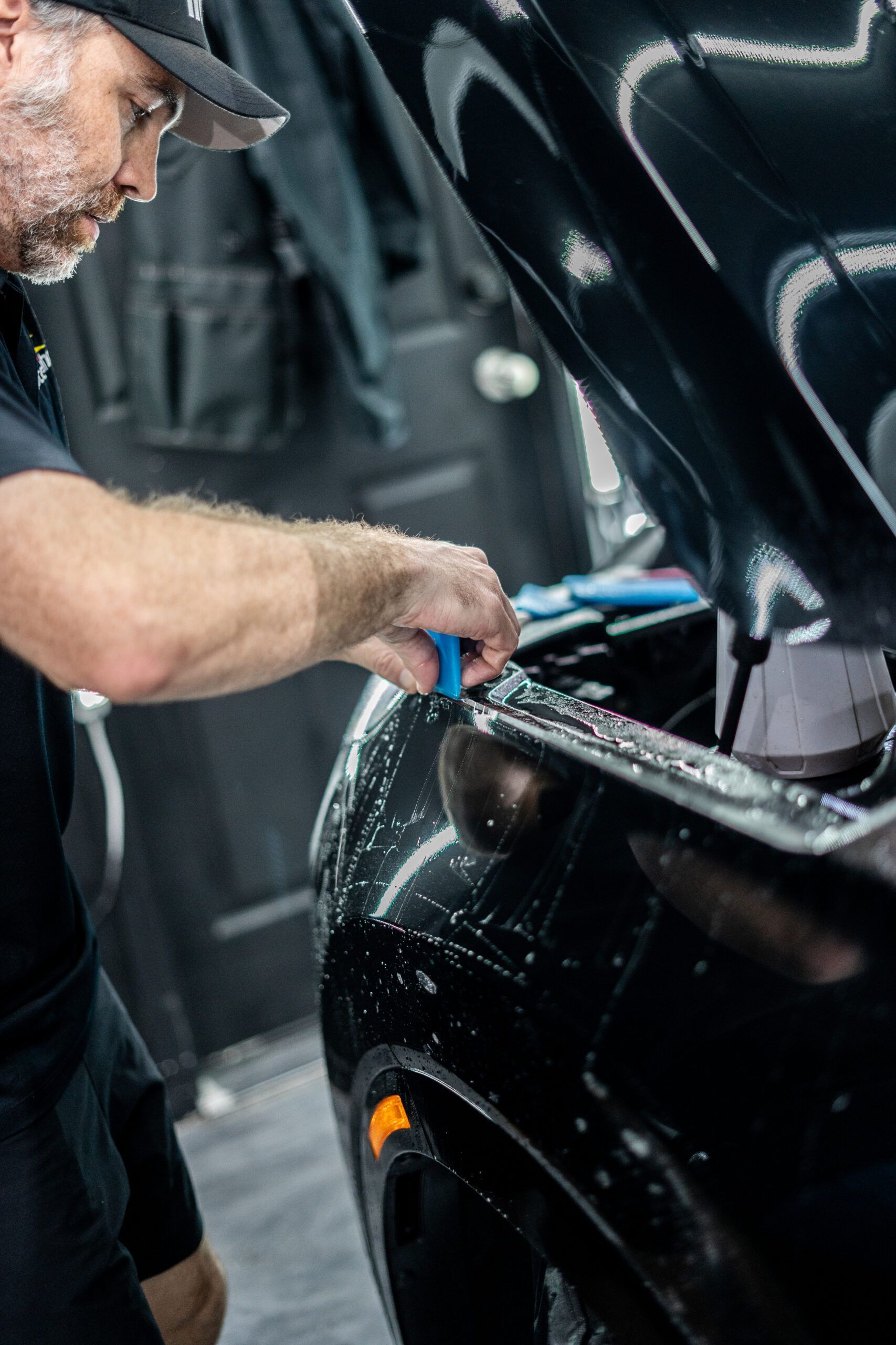 A man is working on a car with the hood open.