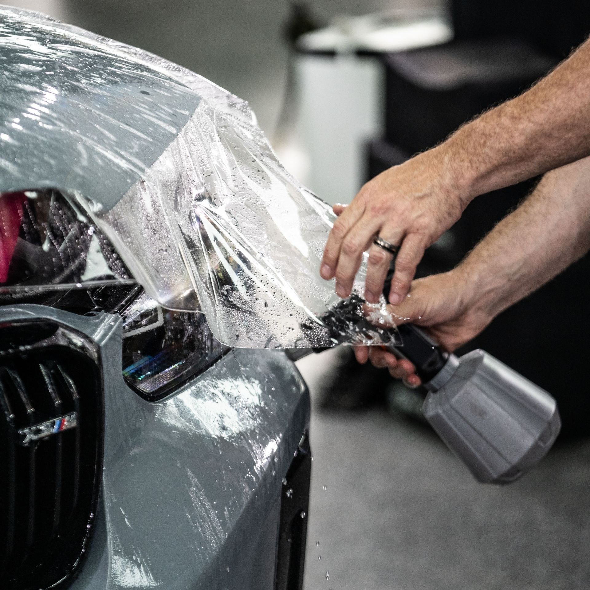A man is working on a blue car in a garage.