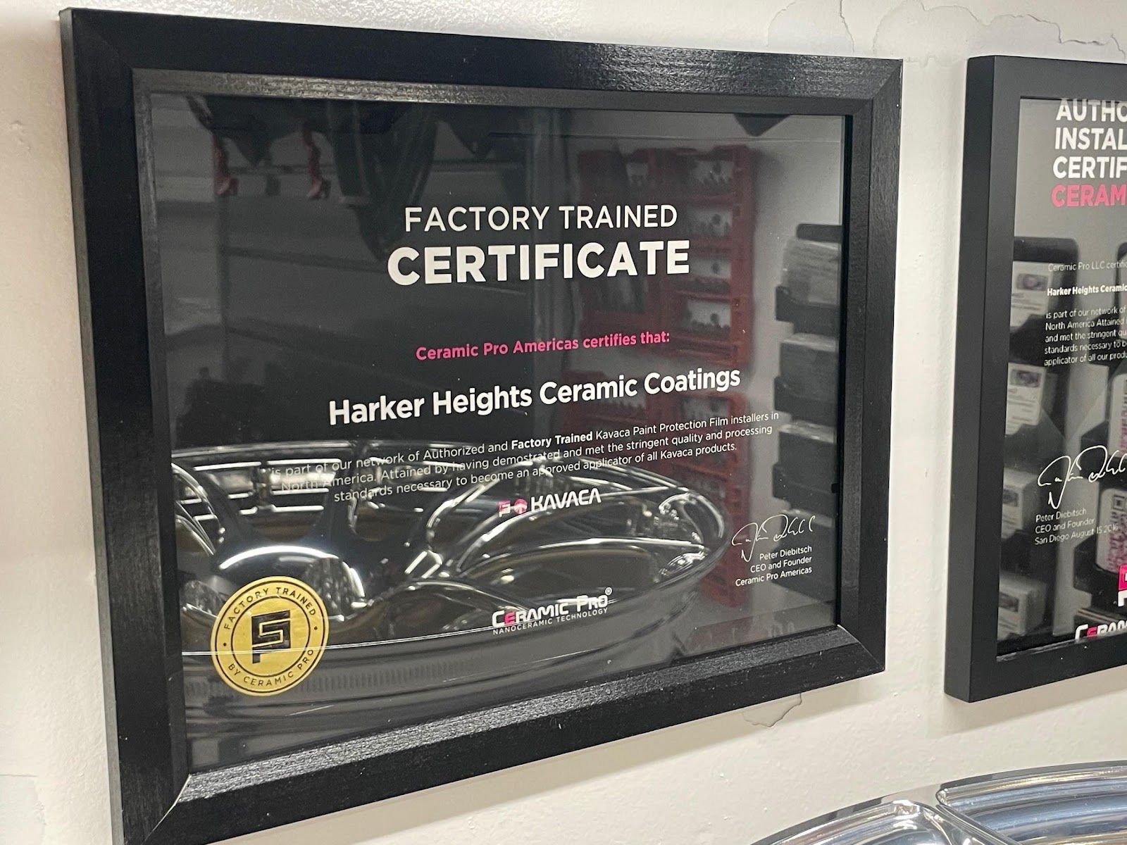 A framed certificate that says factory trained certificate hangs on a wall.