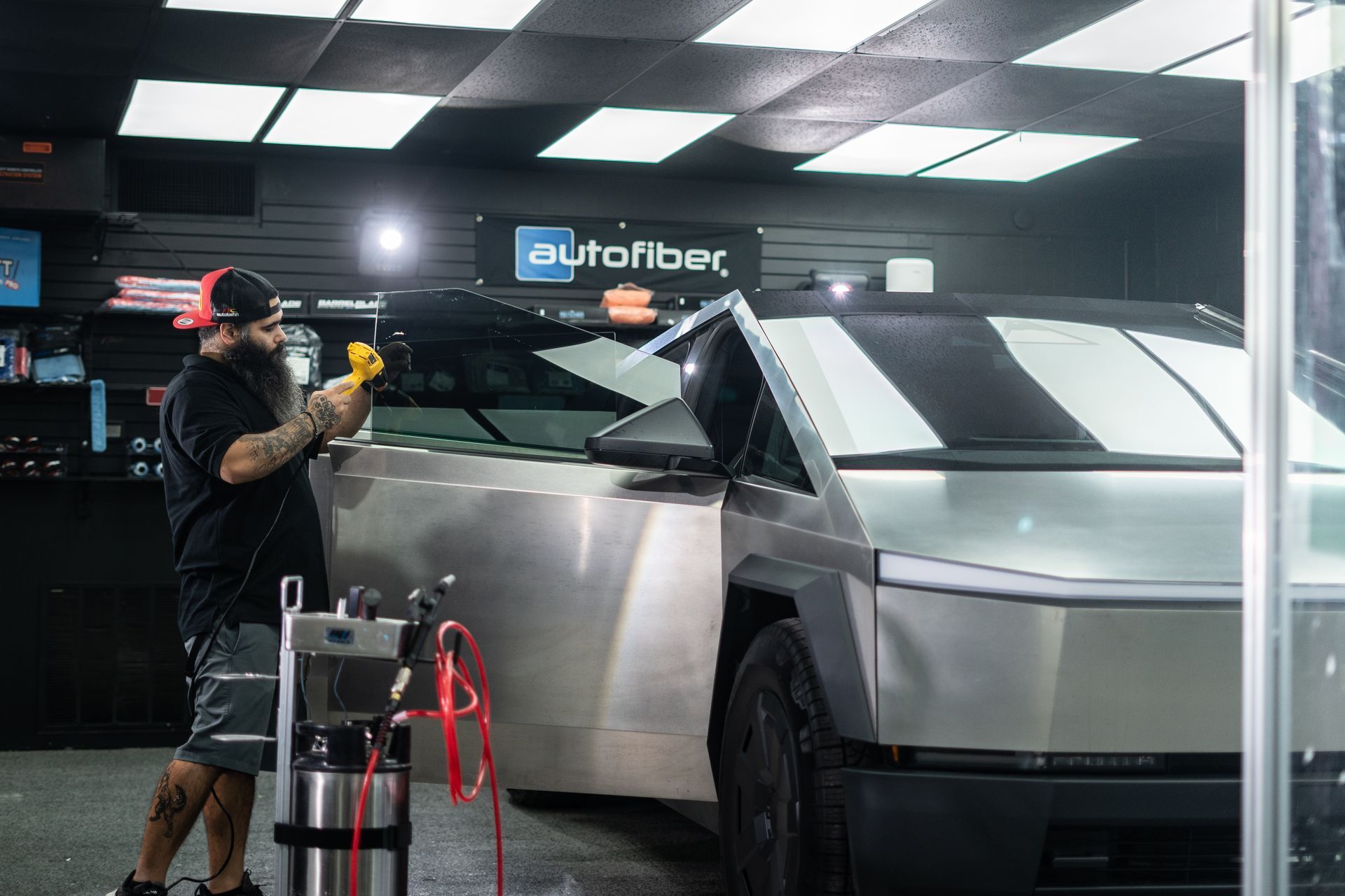 A man is working on a  window tinting forTesla Cybertruck in a garage.