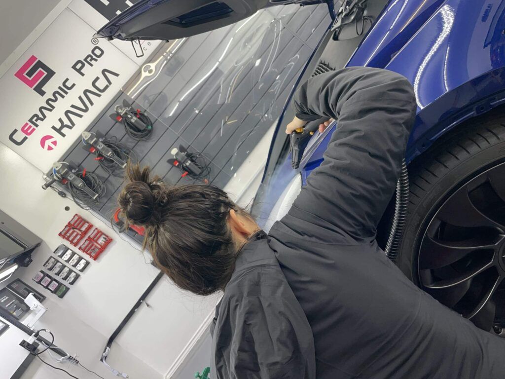 A woman is working on a car in a garage.